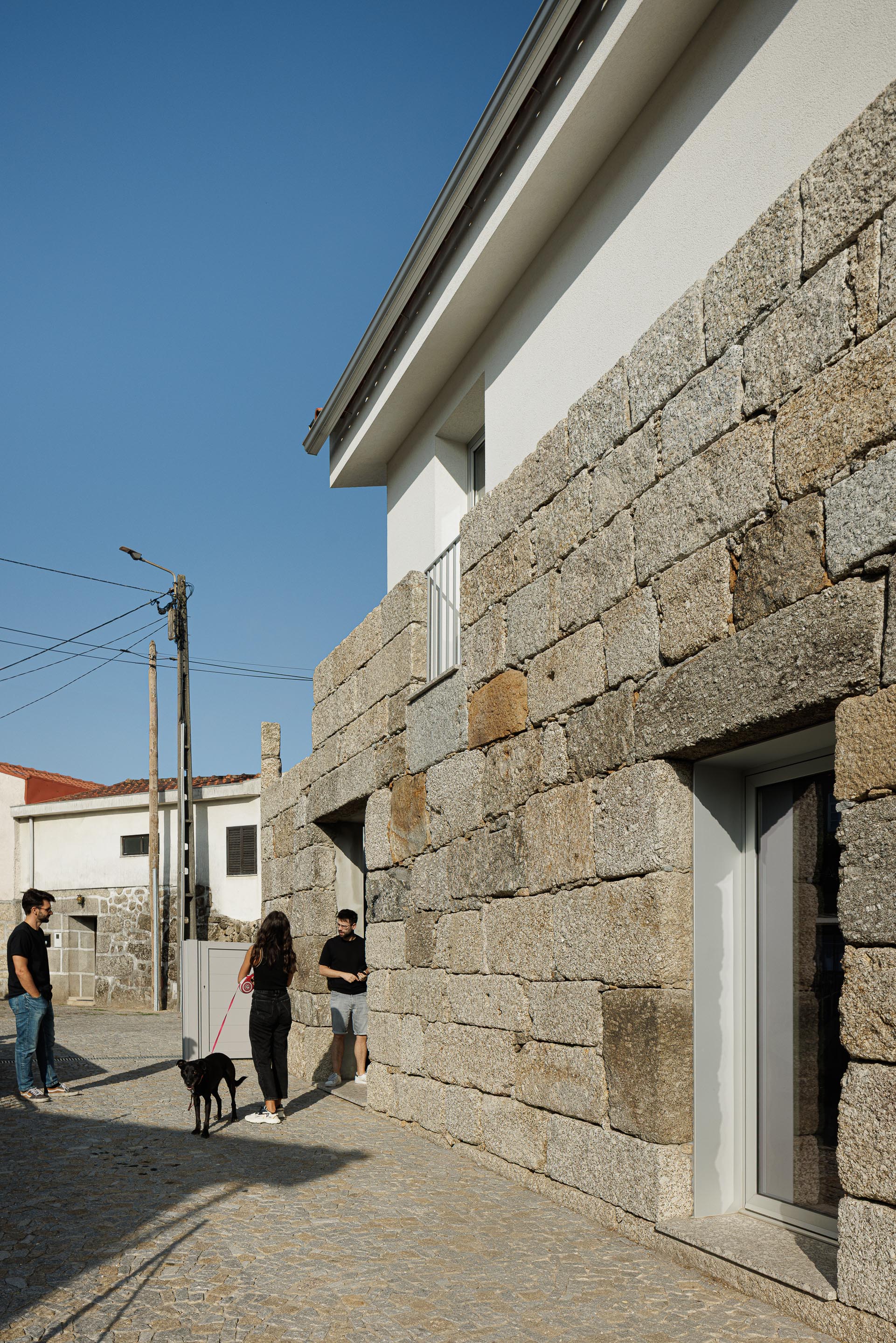 Exterior: Fachada em granito e reboco branco, com detalhes minimalistas e calçada em pedra. — Casa em Mesão Frio arquitetura felixARQS – Daniel Félix Arquitectos em Guimarães