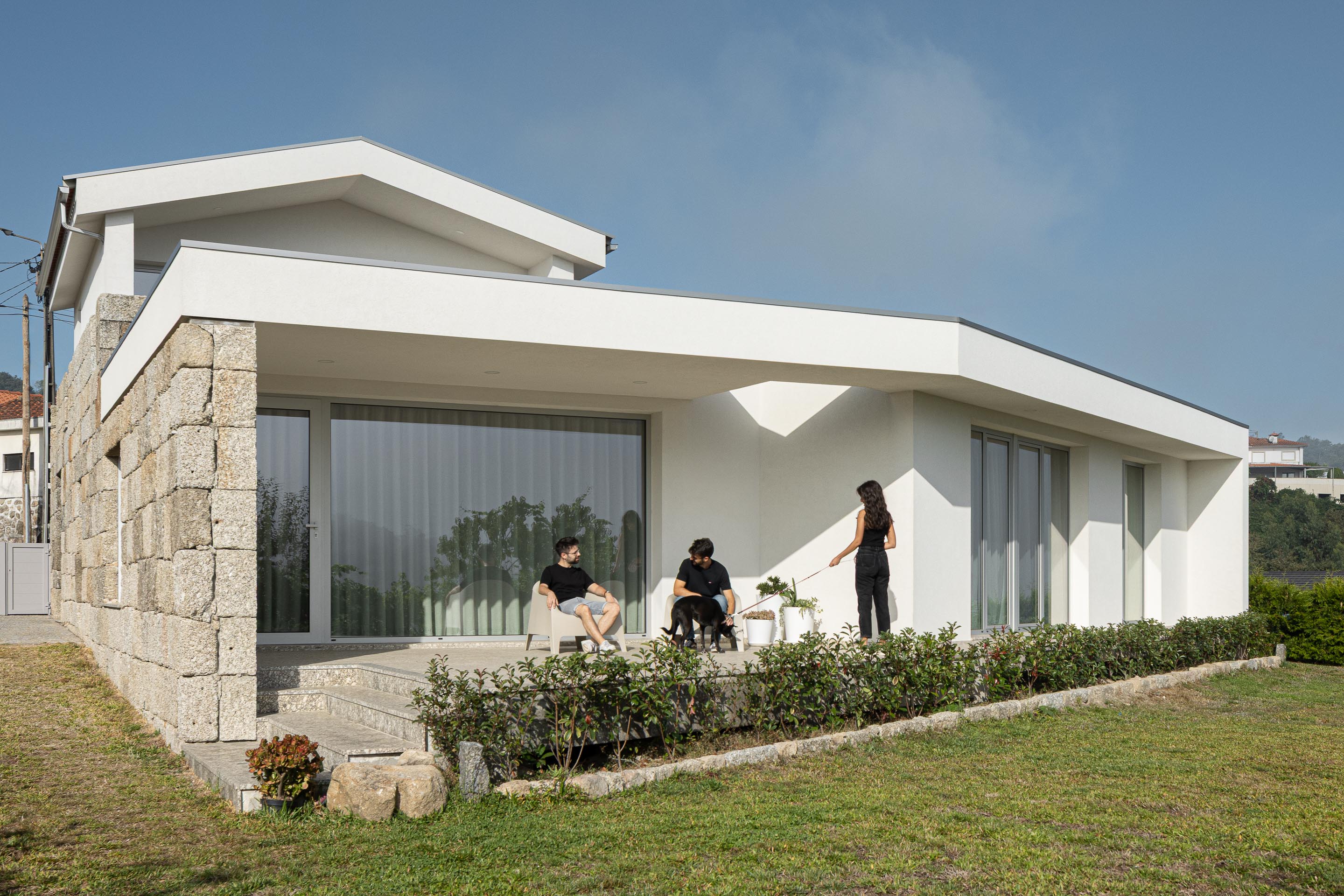 Alpendre: Espaço exterior coberto com pavimento em pedra, cadeiras brancas e vista panorâmica. — Casa em Mesão Frio arquitetura felixARQS – Daniel Félix Arquitectos em Guimarães