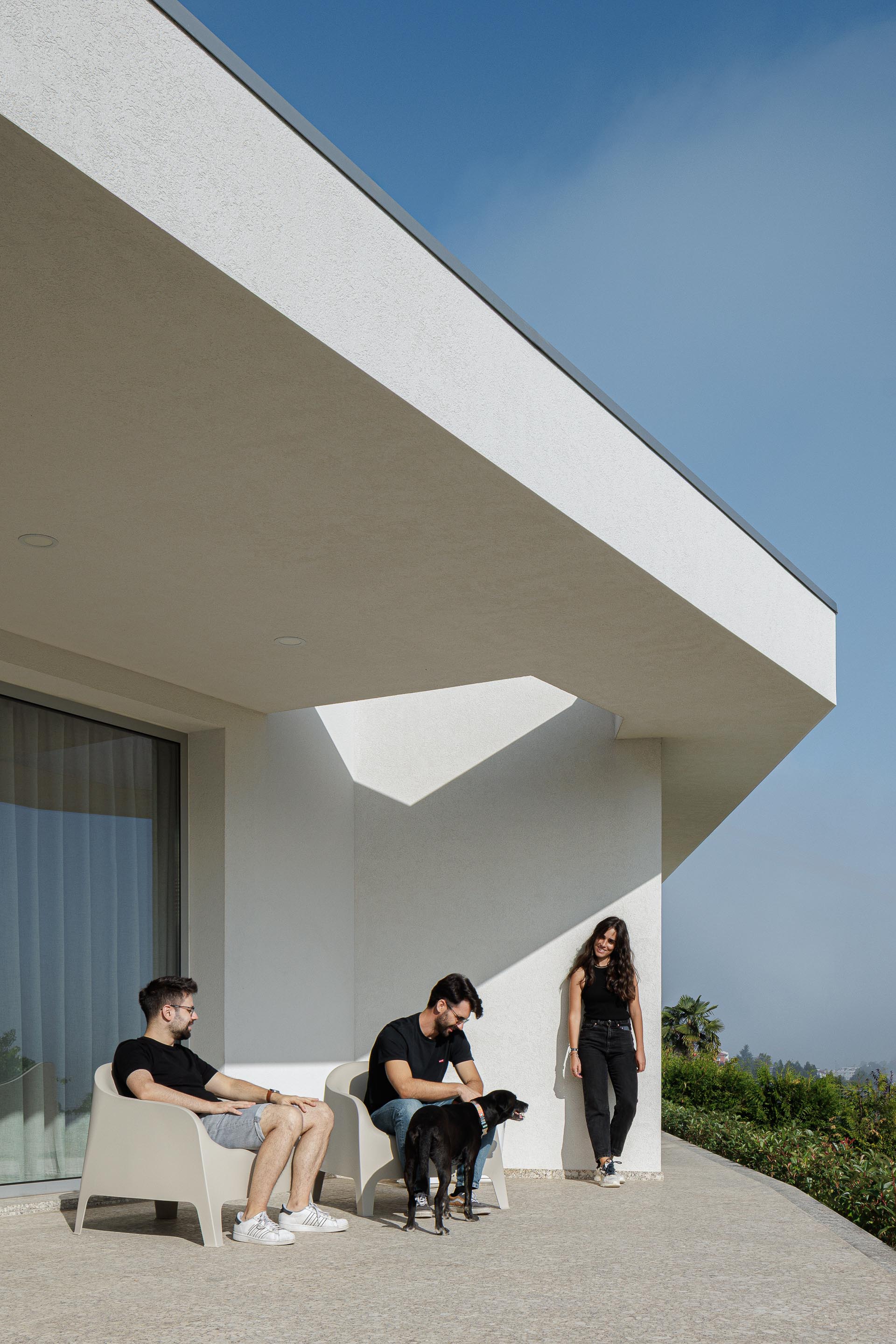 Alpendre: Varanda com pavimento em pedra, cadeiras de design e vista para a paisagem verdejante. — Casa em Mesão Frio arquitetura felixARQS – Daniel Félix Arquitectos em Guimarães