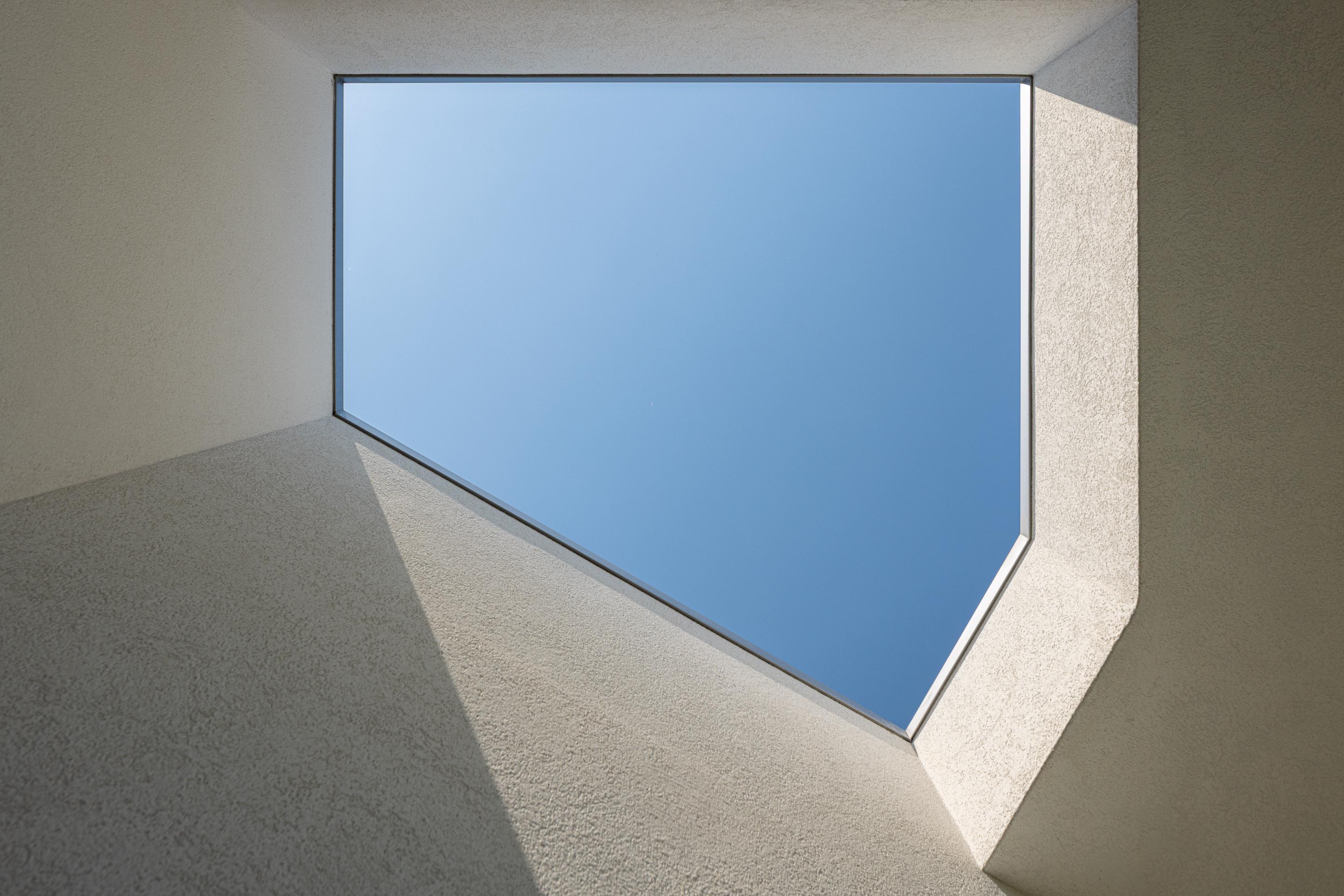 Pátio: Vista para o céu azul através de uma abertura geométrica no teto branco. — Casa em Mesão Frio arquitetura felixARQS – Daniel Félix Arquitectos em Guimarães