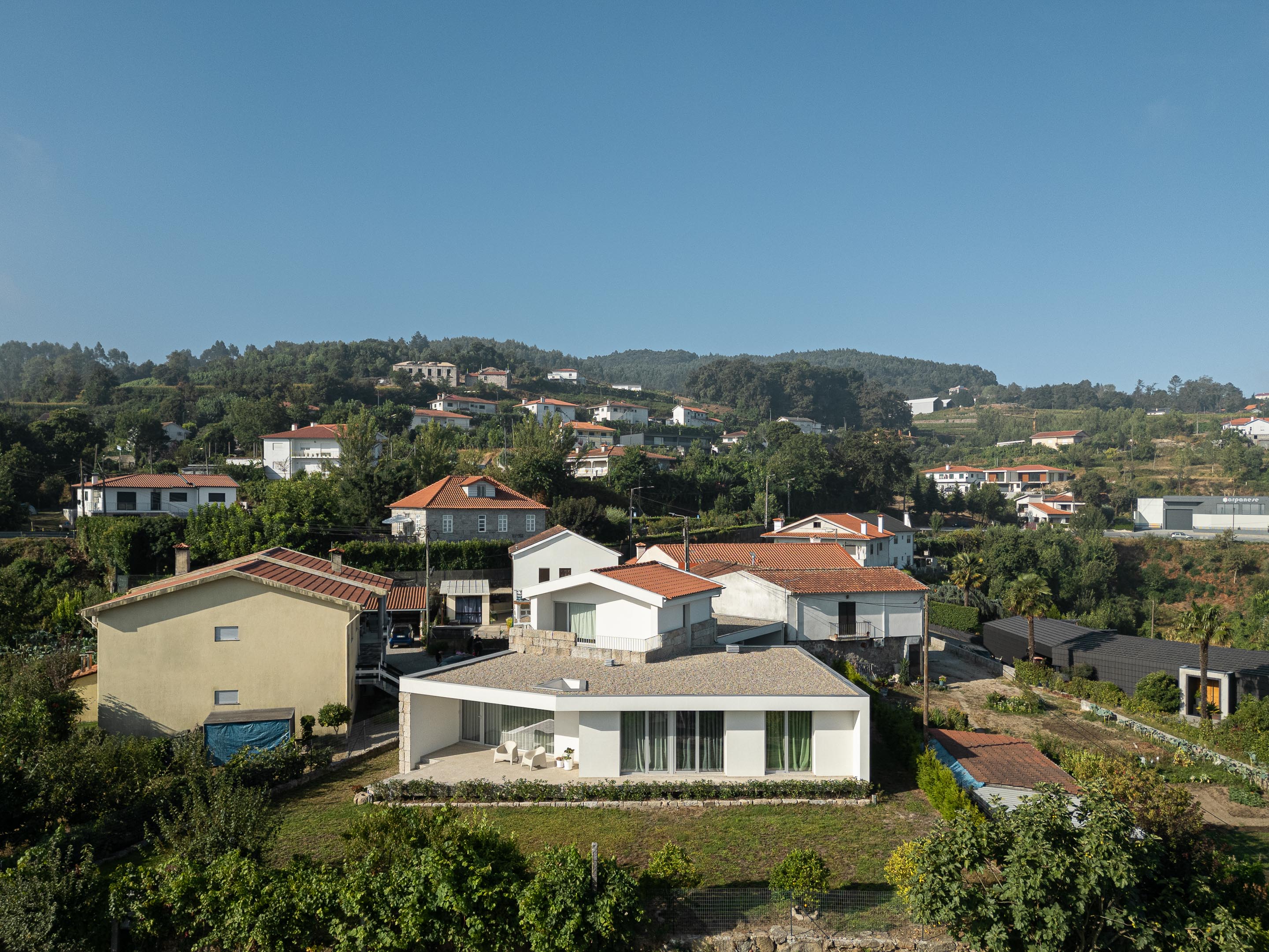 Exterior: Vista aérea da casa integrada na paisagem rural, com telhado de duas águas e alpendre. — Casa em Mesão Frio arquitetura felixARQS – Daniel Félix Arquitectos em Guimarães