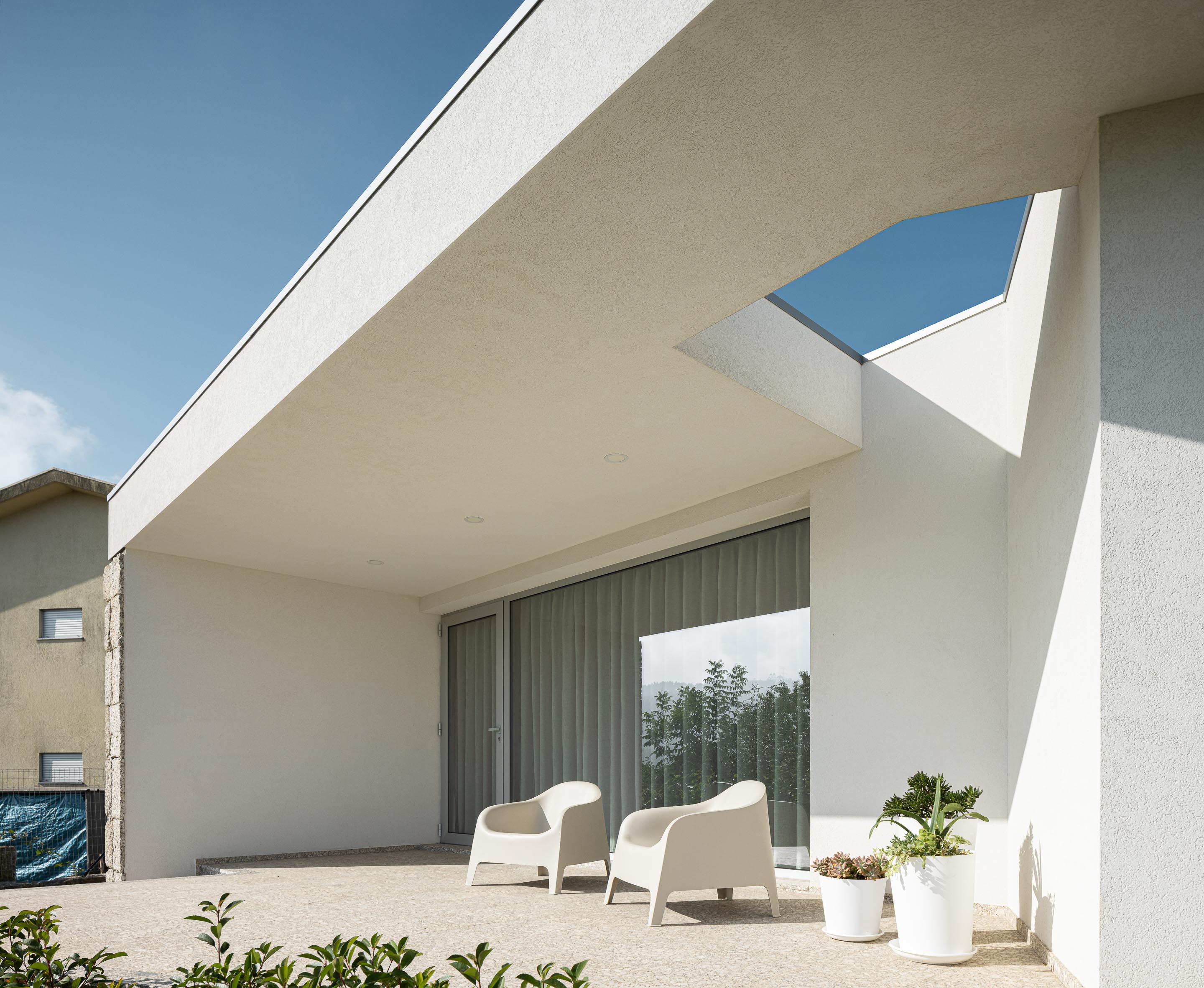 Alpendre: Detalhe do alpendre com cadeiras de design, plantas em vasos brancos e teto branco. — Casa em Mesão Frio arquitetura felixARQS – Daniel Félix Arquitectos em Guimarães