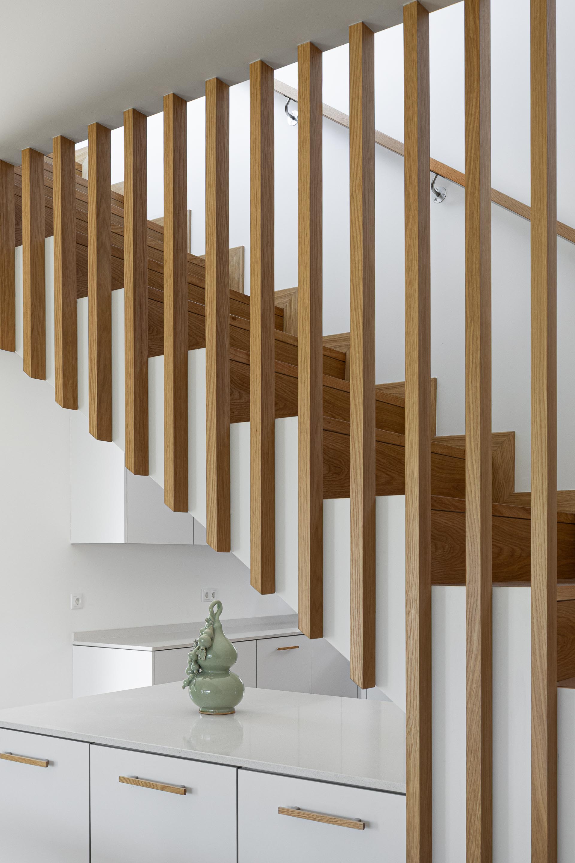 Escadas: Detalhe das escadas em madeira com ripas verticais, integradas na cozinha moderna. — Casa em Mesão Frio arquitetura felixARQS – Daniel Félix Arquitectos em Guimarães