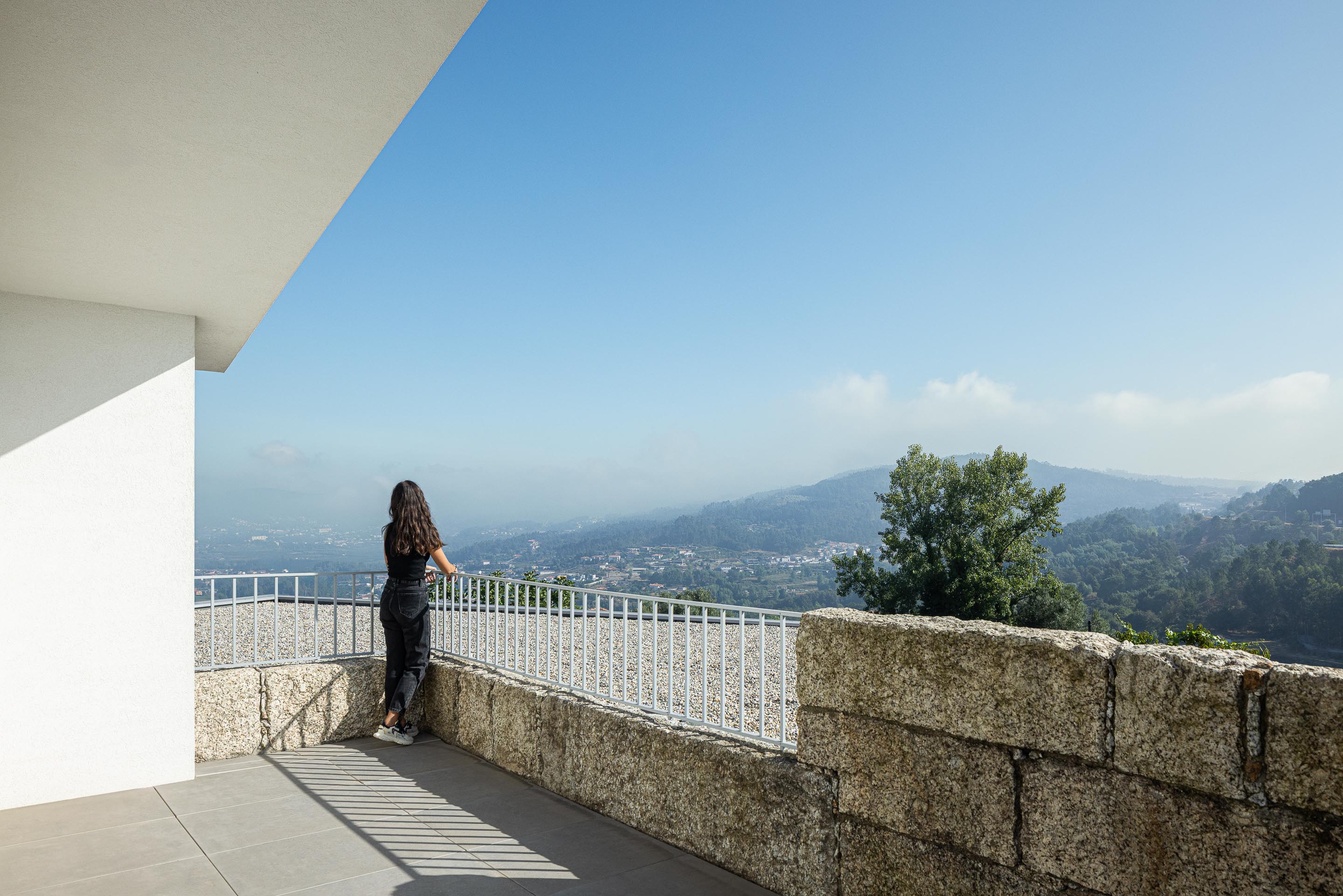 Varanda: Vista panorâmica da varanda com grade branca e paisagem verdejante ao fundo. — Casa em Mesão Frio arquitetura felixARQS – Daniel Félix Arquitectos em Guimarães