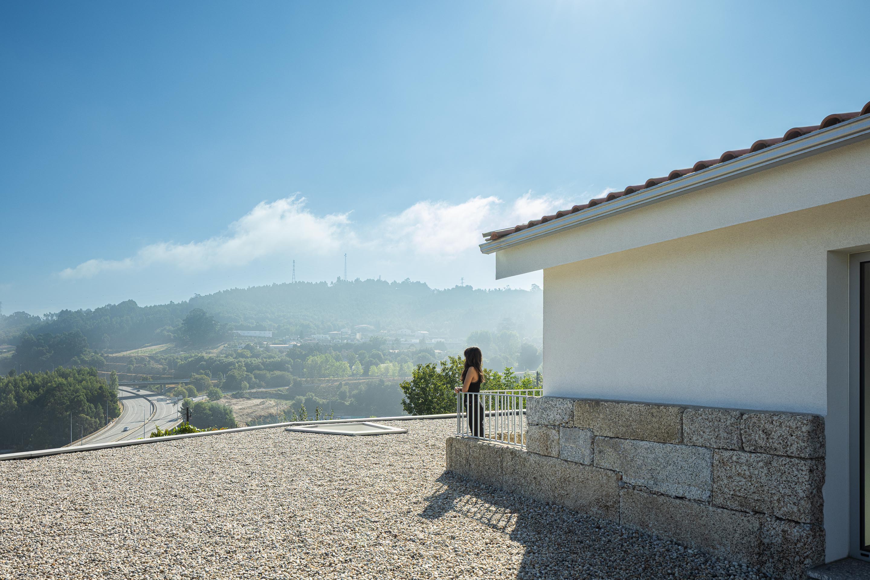 Exterior: Vista da casa com telhado de duas águas, varanda e paisagem montanhosa. — Casa em Mesão Frio arquitetura felixARQS – Daniel Félix Arquitectos em Guimarães