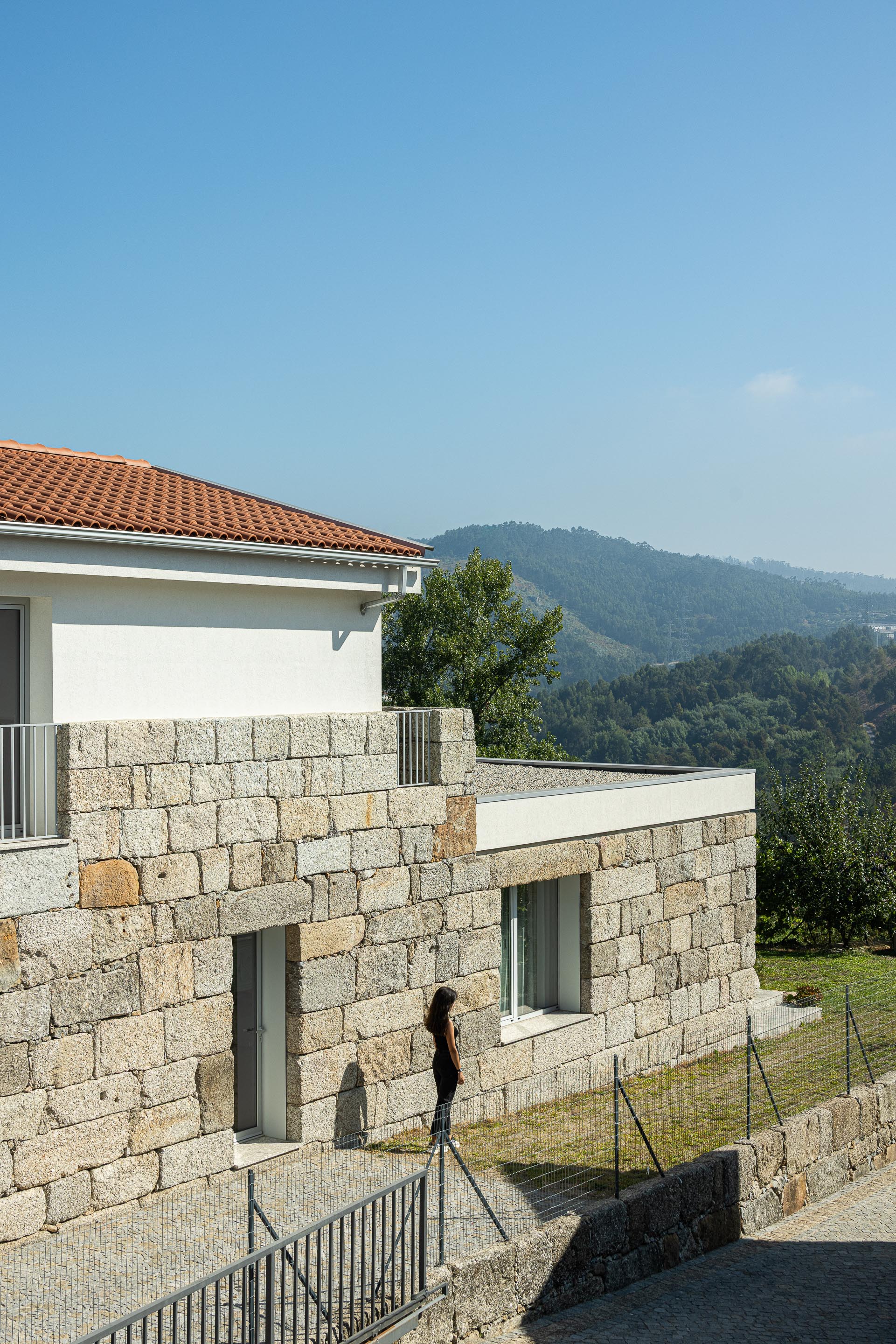 Exterior: Fachada em granito com varanda, telhado de duas águas e vista para a paisagem. — Casa em Mesão Frio arquitetura felixARQS – Daniel Félix Arquitectos em Guimarães
