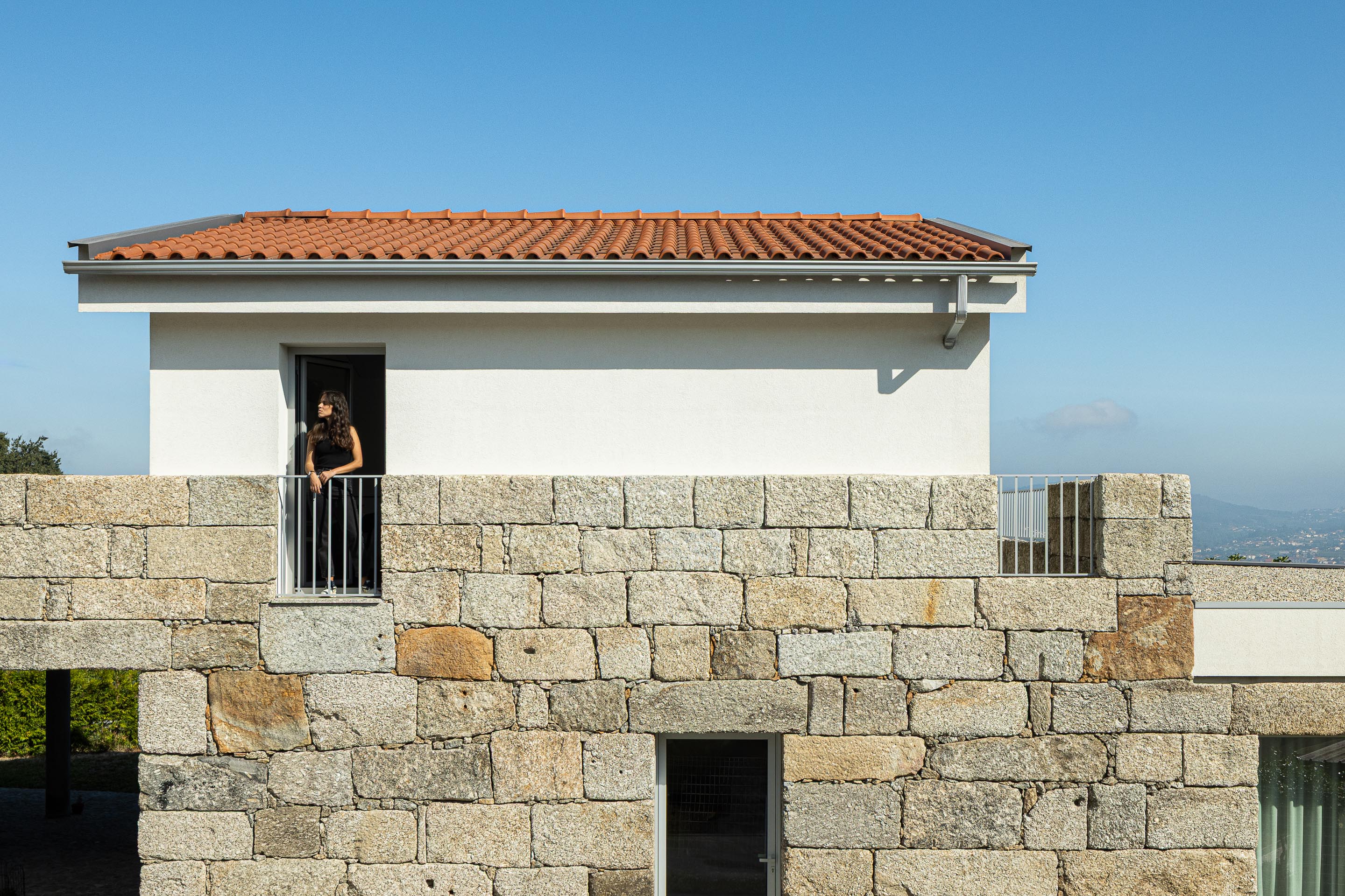 Varanda: Detalhe da varanda com grade branca, fachada em granito e vista para a paisagem. — Casa em Mesão Frio arquitetura felixARQS – Daniel Félix Arquitectos em Guimarães