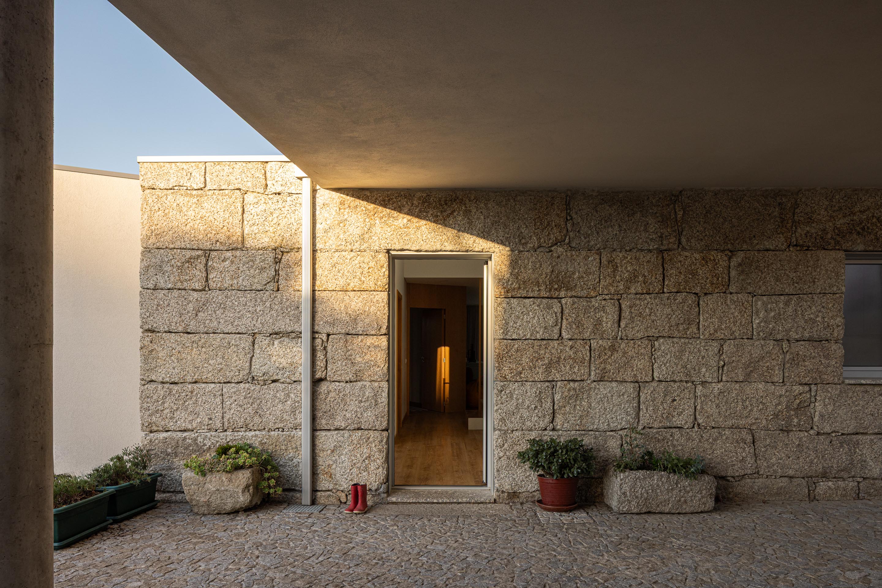 Exterior: Garagem coberta com carro clássico, pavimento em pedra e jardim ao fundo. — Casa em Mesão Frio arquitetura felixARQS – Daniel Félix Arquitectos em Guimarães