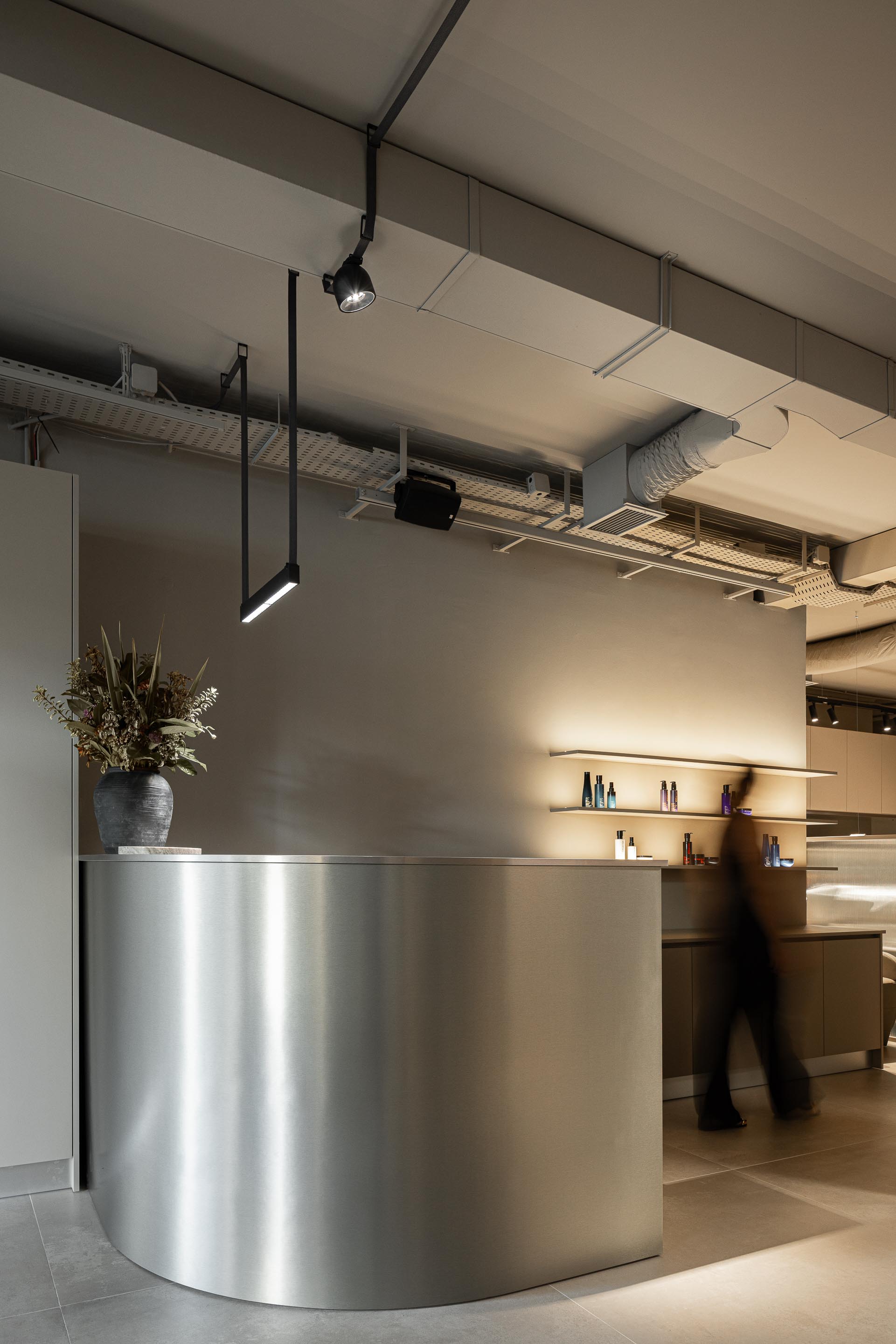 Recepção: Balcão de receção em metal, iluminação indireta e teto com infraestruturas expostas. — Vasco Freitas Salon arquitetura MAT Arquitetura e Interiores em Porto
