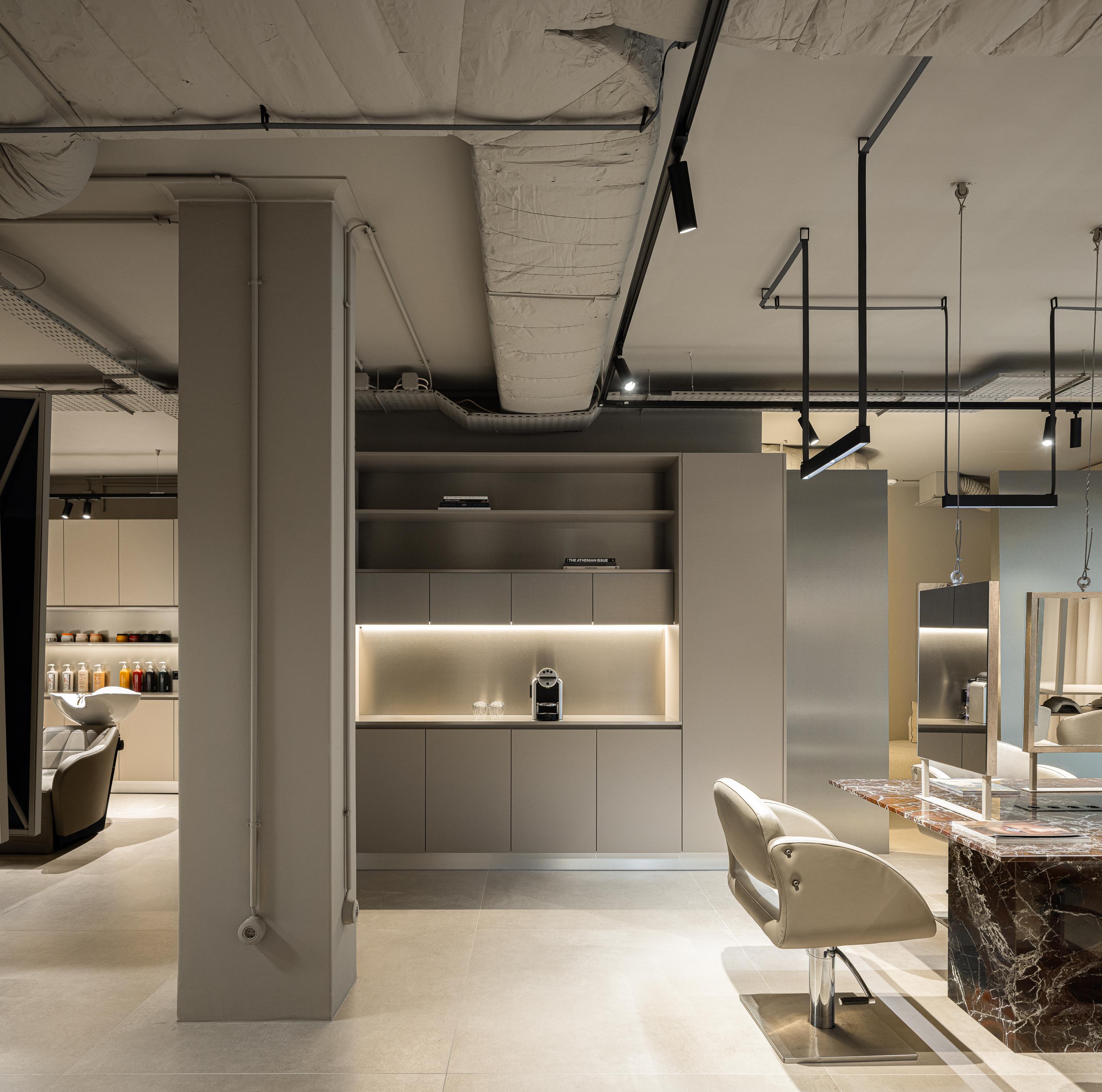 Salão: Vista geral do salão com espaços de trabalho, divisórias metálicas curvas e cortinas. — Vasco Freitas Salon arquitetura MAT Arquitetura e Interiores em Porto