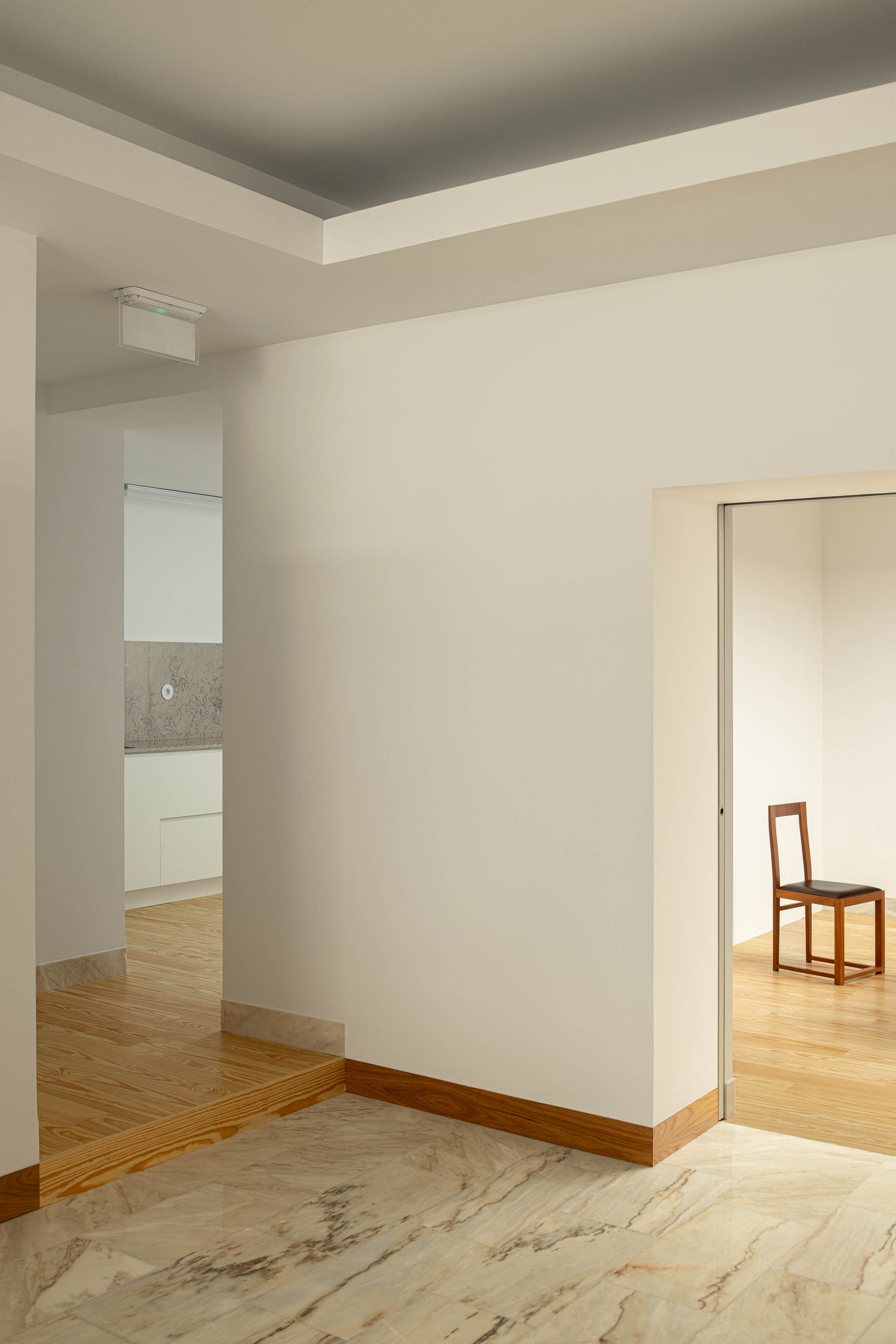 Corredor com pavimento em mármore e acesso à cozinha e sala de reuniões. — Reconversão do Talho Central arquitetura José Pedro Lima Arquiteto em Coimbra