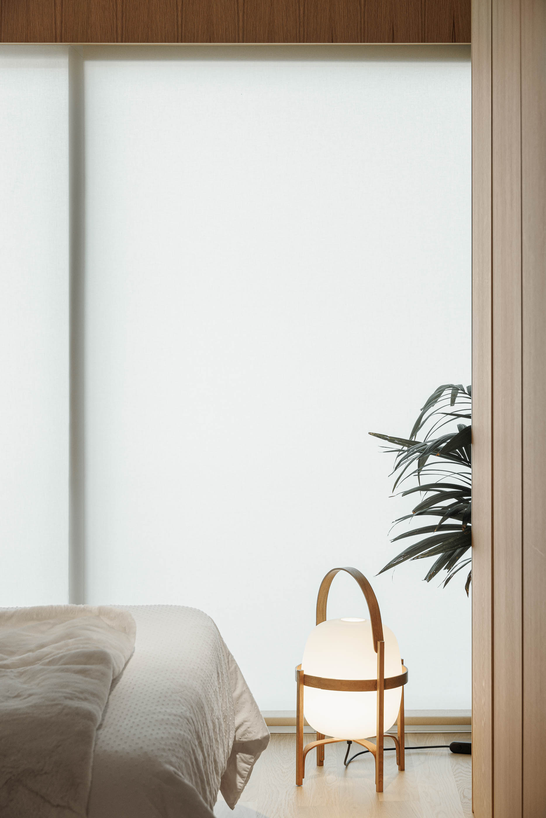 Quarto: Candeeiro de pé esférico com estrutura em madeira, planta e cortina translúcida junto à cama. — Barra Apartment arquitetura Paulo Martins Arquitectura e Design em Aveiro