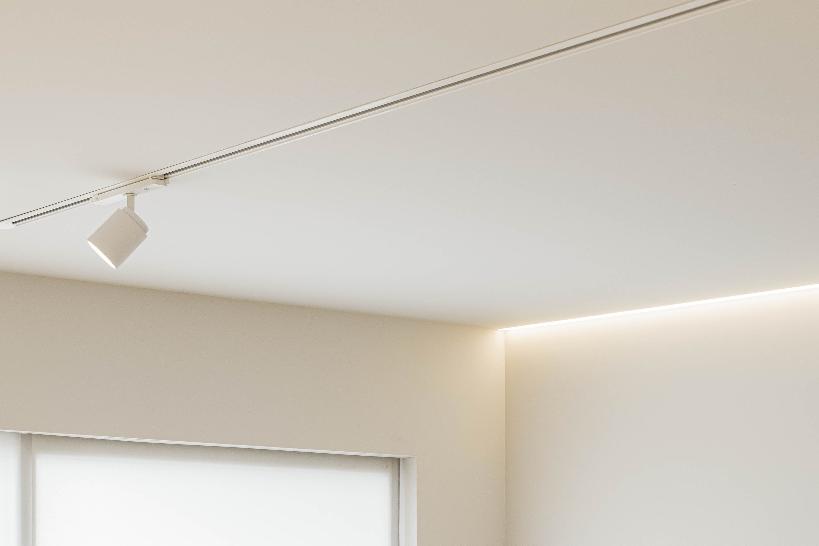 Teto: Candeeiro de teto direcionável e iluminação embutida no teto branco. — Barra Apartment arquitetura Paulo Martins Arquitectura e Design em Aveiro