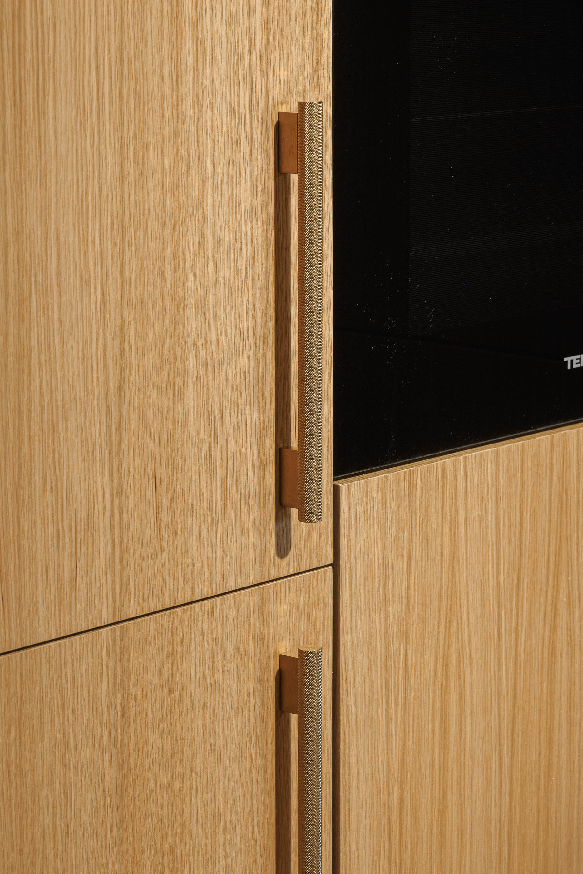 Cozinha: Detalhe dos puxadores texturizados dos armários em madeira clara da cozinha. — Barra Apartment arquitetura Paulo Martins Arquitectura e Design em Aveiro