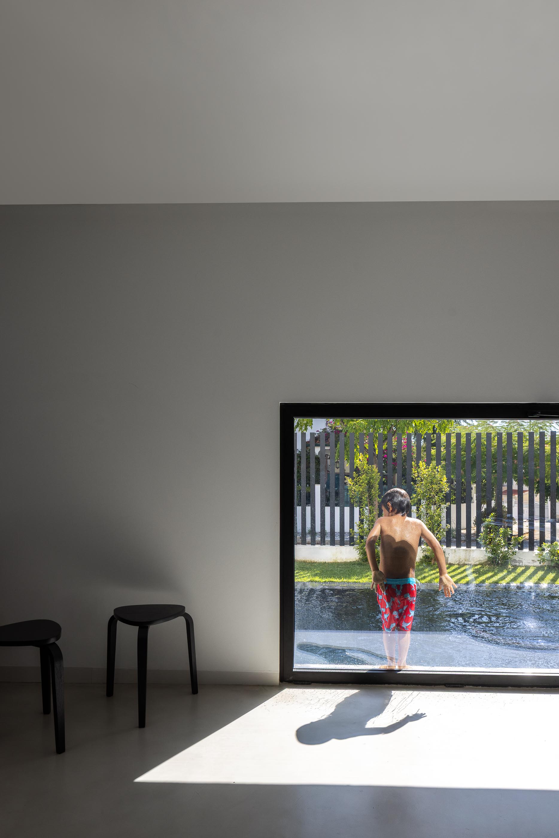Exterior: Crianças na piscina preta com relvado e vedação ao fundo. — Casa DR arquitetura NMDARQ – Nuno Miguel Dias, Arquitecto em Torres Novas