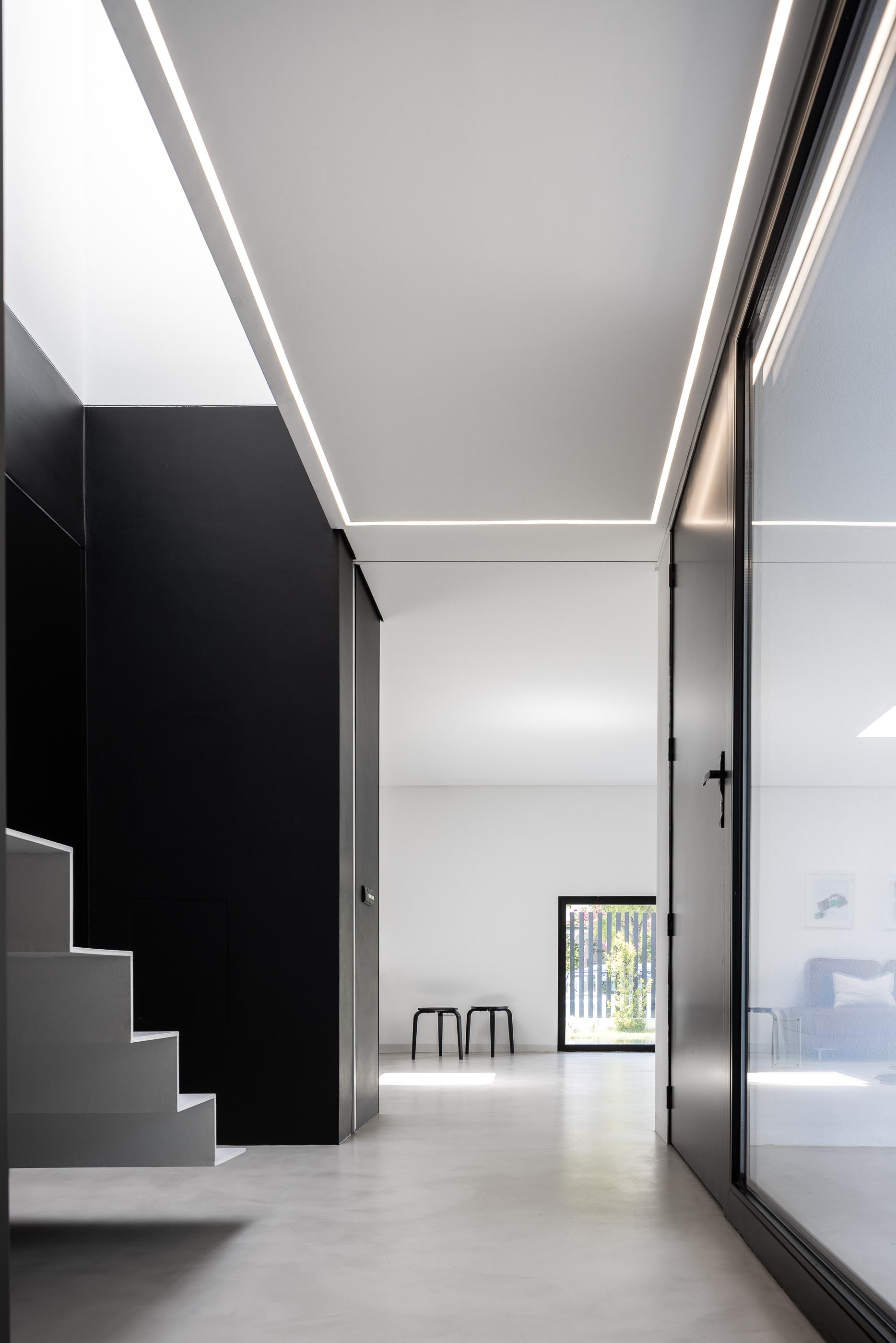Escadas: Detalhe das escadas brancas com parede preta e luz natural. — Casa DR arquitetura NMDARQ – Nuno Miguel Dias, Arquitecto em Torres Novas