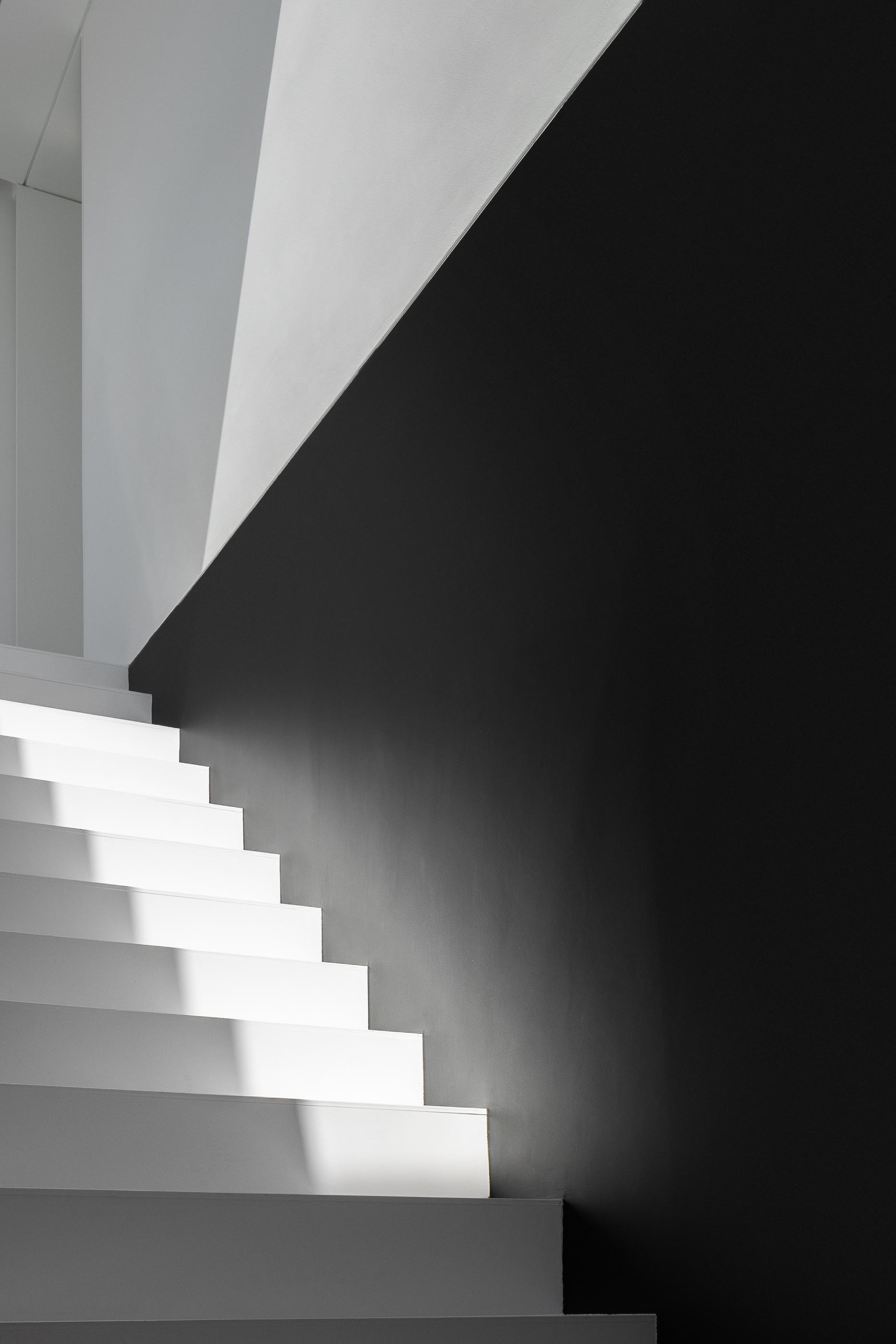 Corredor: Corredor branco com claraboia, guarda branca e pavimento cinza. — Casa DR arquitetura NMDARQ – Nuno Miguel Dias, Arquitecto em Torres Novas