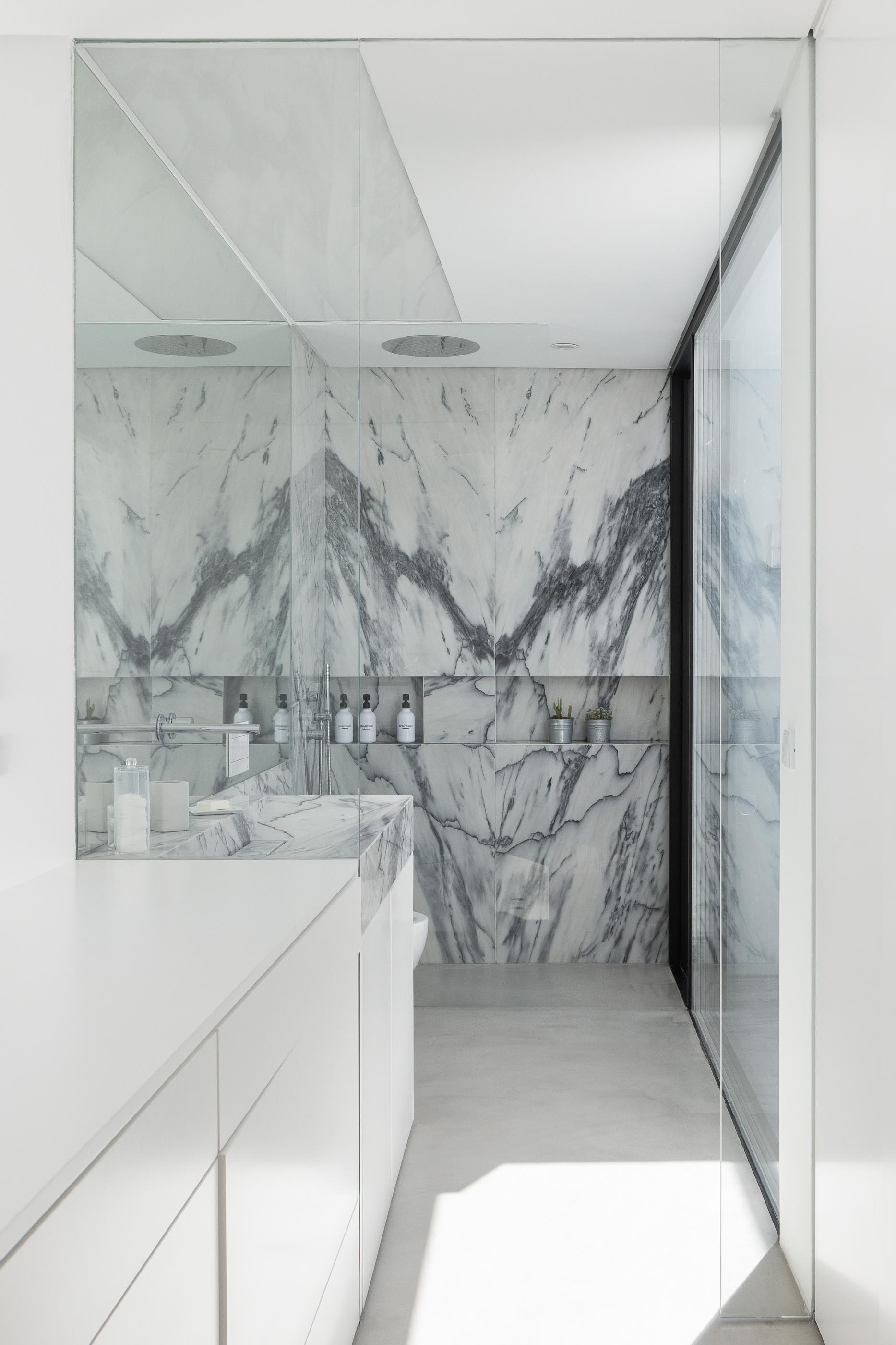 Casa de banho: Duche com revestimento em mármore, chuveiro de teto e bidet. — Casa DR arquitetura NMDARQ – Nuno Miguel Dias, Arquitecto em Torres Novas
