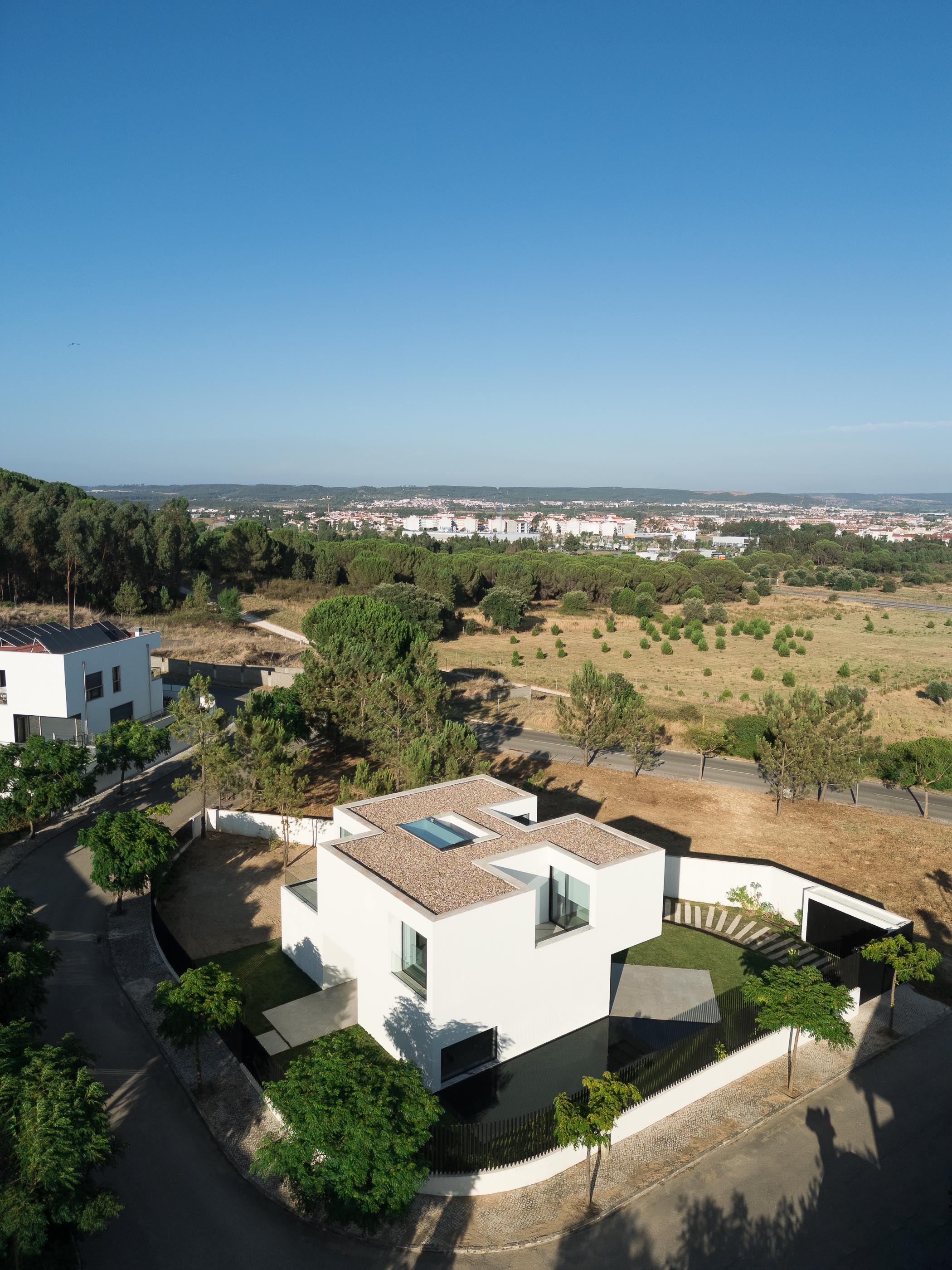 Exterior: Casa branca minimalista com garagem e relvado ao entardecer. — Casa DR arquitetura NMDARQ – Nuno Miguel Dias, Arquitecto em Torres Novas