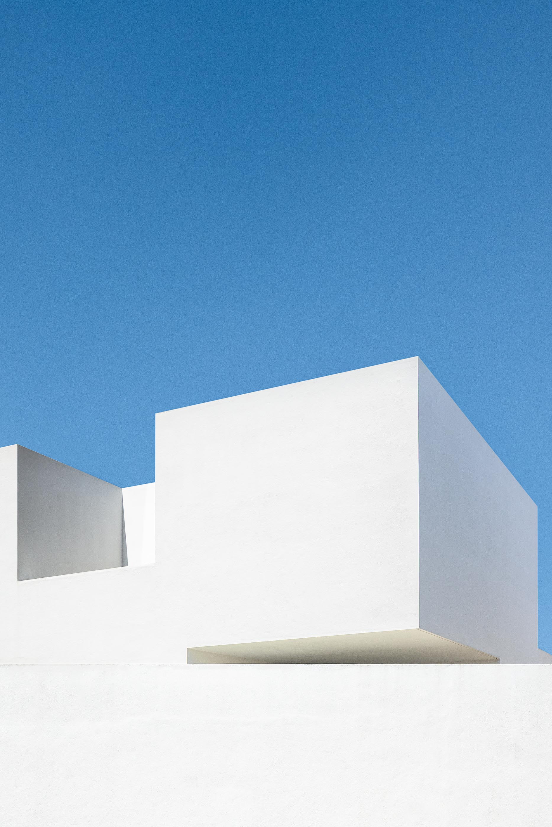 Exterior: Casa branca minimalista com piscina, garagem e janelas amplas ao entardecer. — Casa DR arquitetura NMDARQ – Nuno Miguel Dias, Arquitecto em Torres Novas