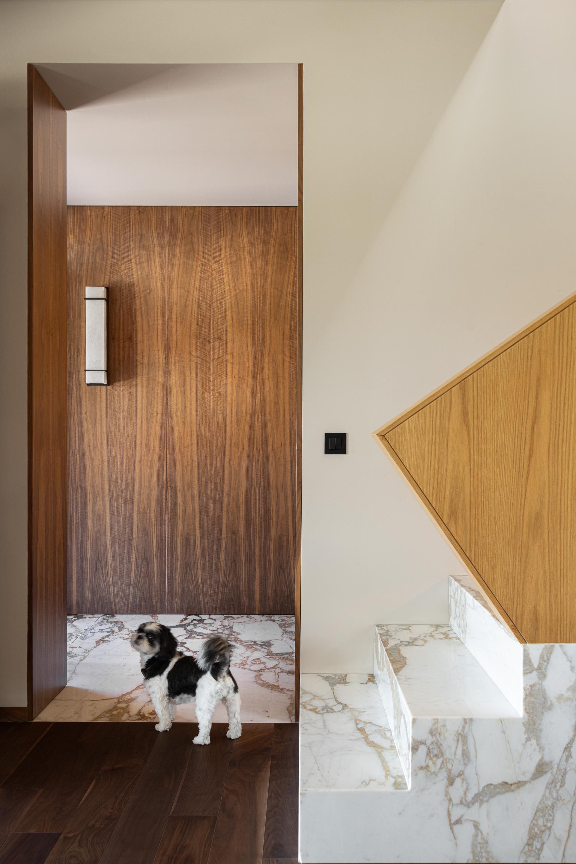 Hall de entrada: Pavimento em mármore e madeira, parede em madeira com aplique de luz e escadas com detalhes em mármore. — Casa do Engenho arquitetura silverline em Vila Nova de Gaia