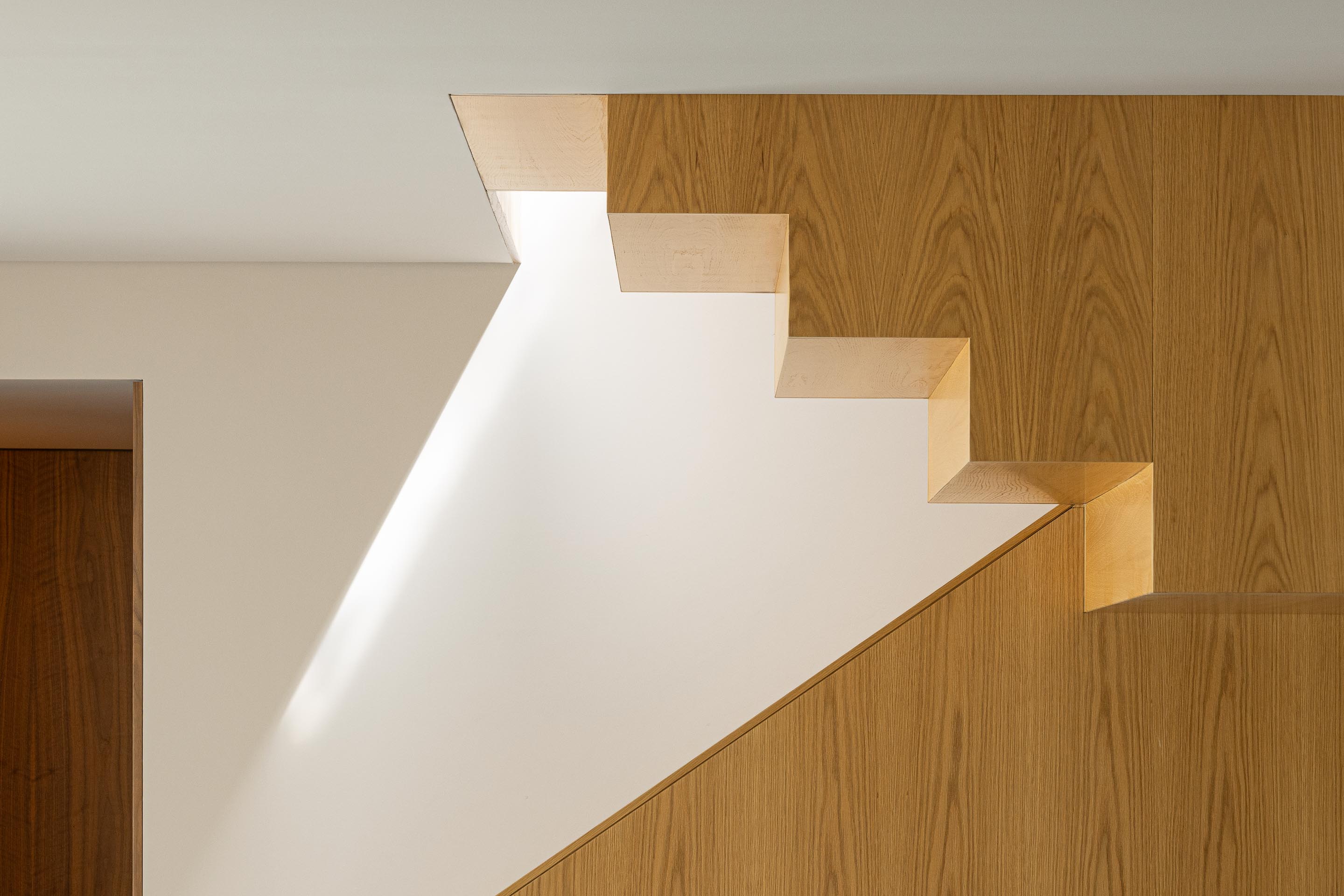 Escadas: Detalhe da estrutura em madeira clara, com iluminação natural através de abertura na parede. — Casa do Engenho arquitetura silverline em Vila Nova de Gaia