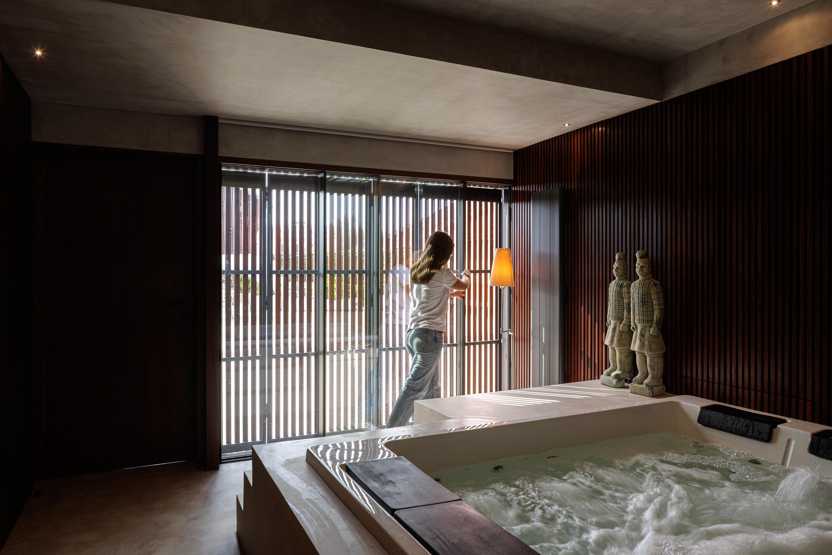 Spa: Banheira de hidromassagem, parede revestida em ripas de madeira escura e persianas venezianas. — Casa do Engenho arquitetura silverline em Vila Nova de Gaia
