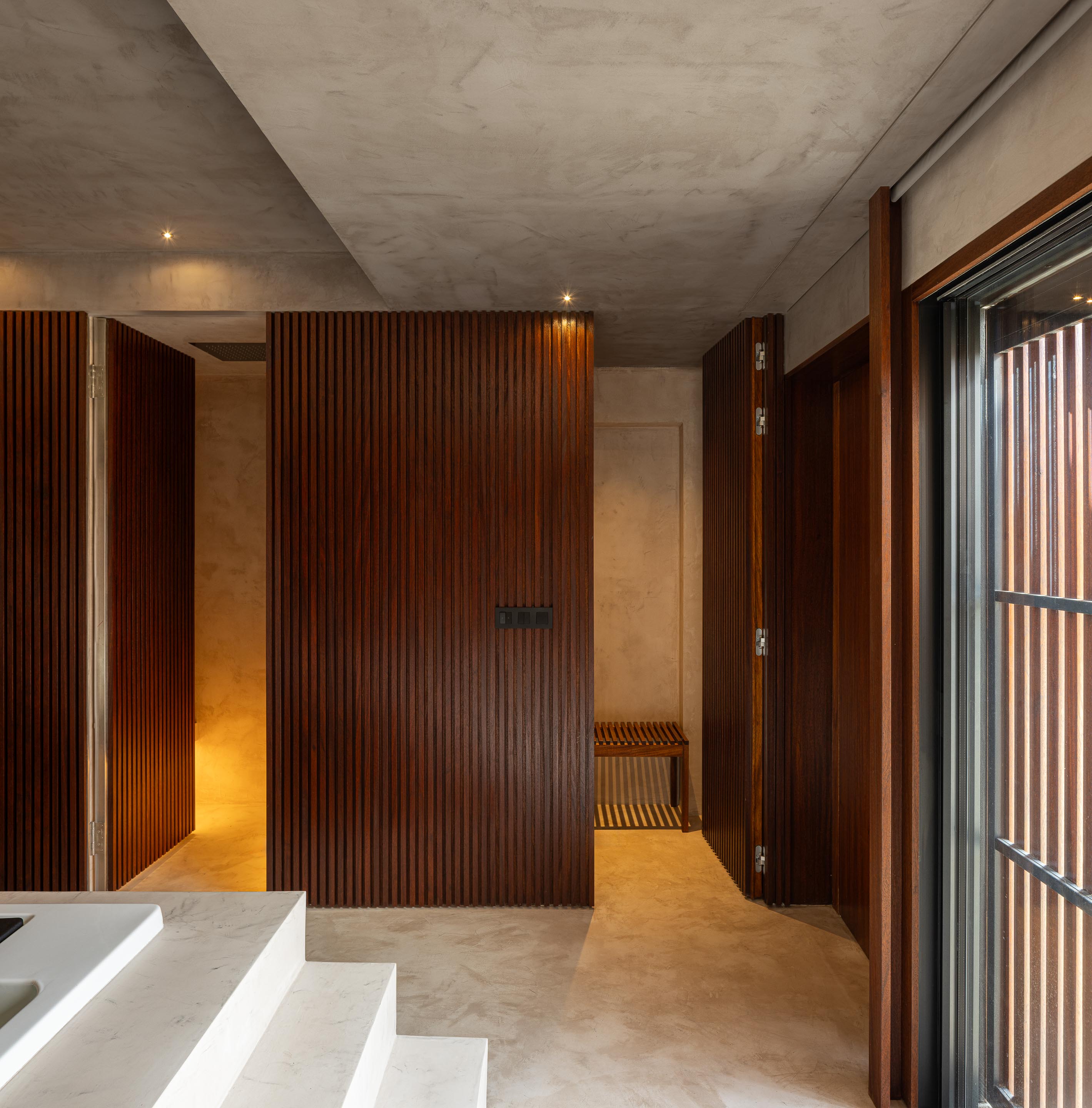 Spa: Interior com portas em ripas de madeira escura, pavimento em cimento afagado e banco em madeira. — Casa do Engenho arquitetura silverline em Vila Nova de Gaia