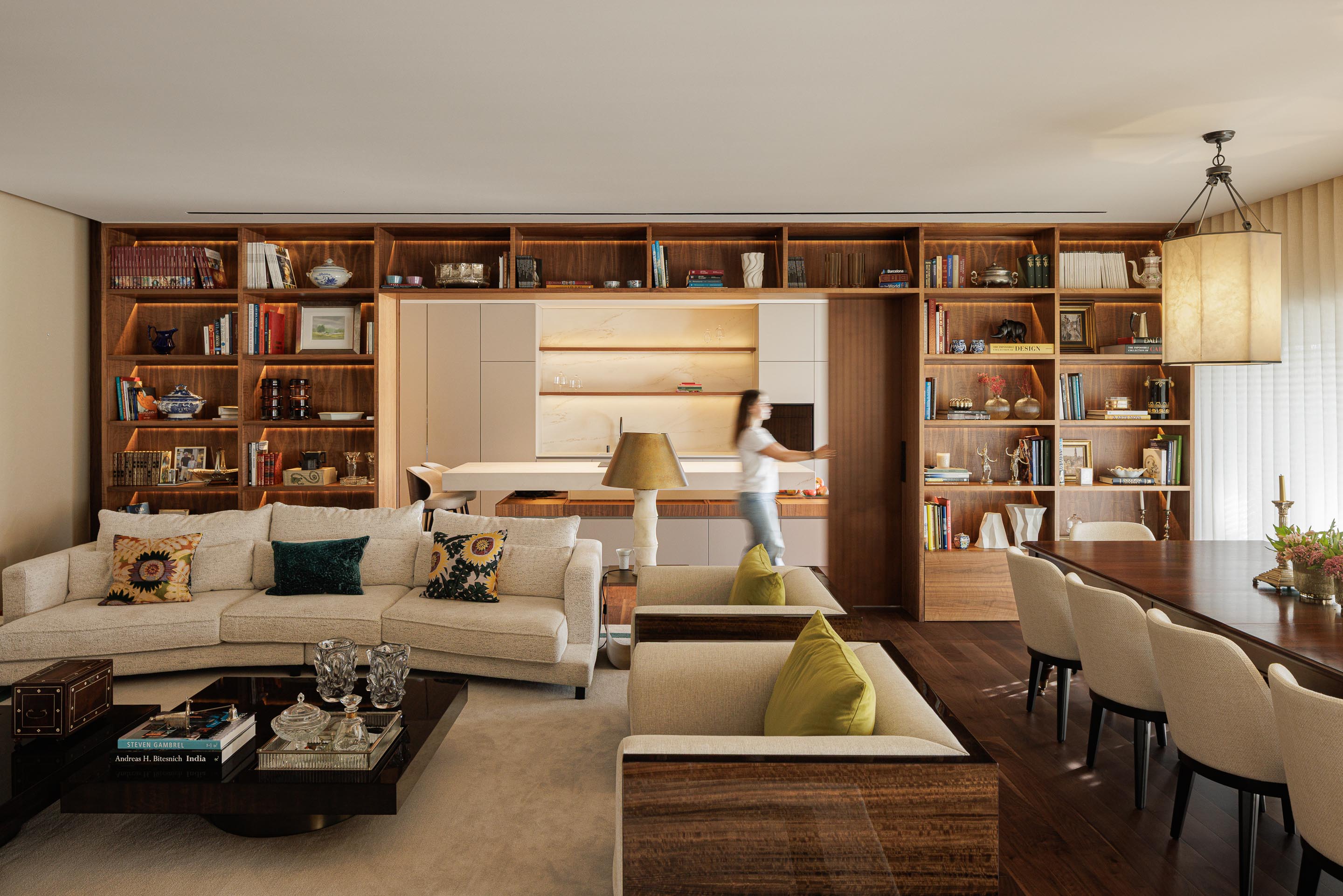 Sala de estar: Espaço amplo com estantes em madeira escura, sofá branco, cadeirões bege e mesa de jantar. — Casa do Engenho arquitetura silverline em Vila Nova de Gaia