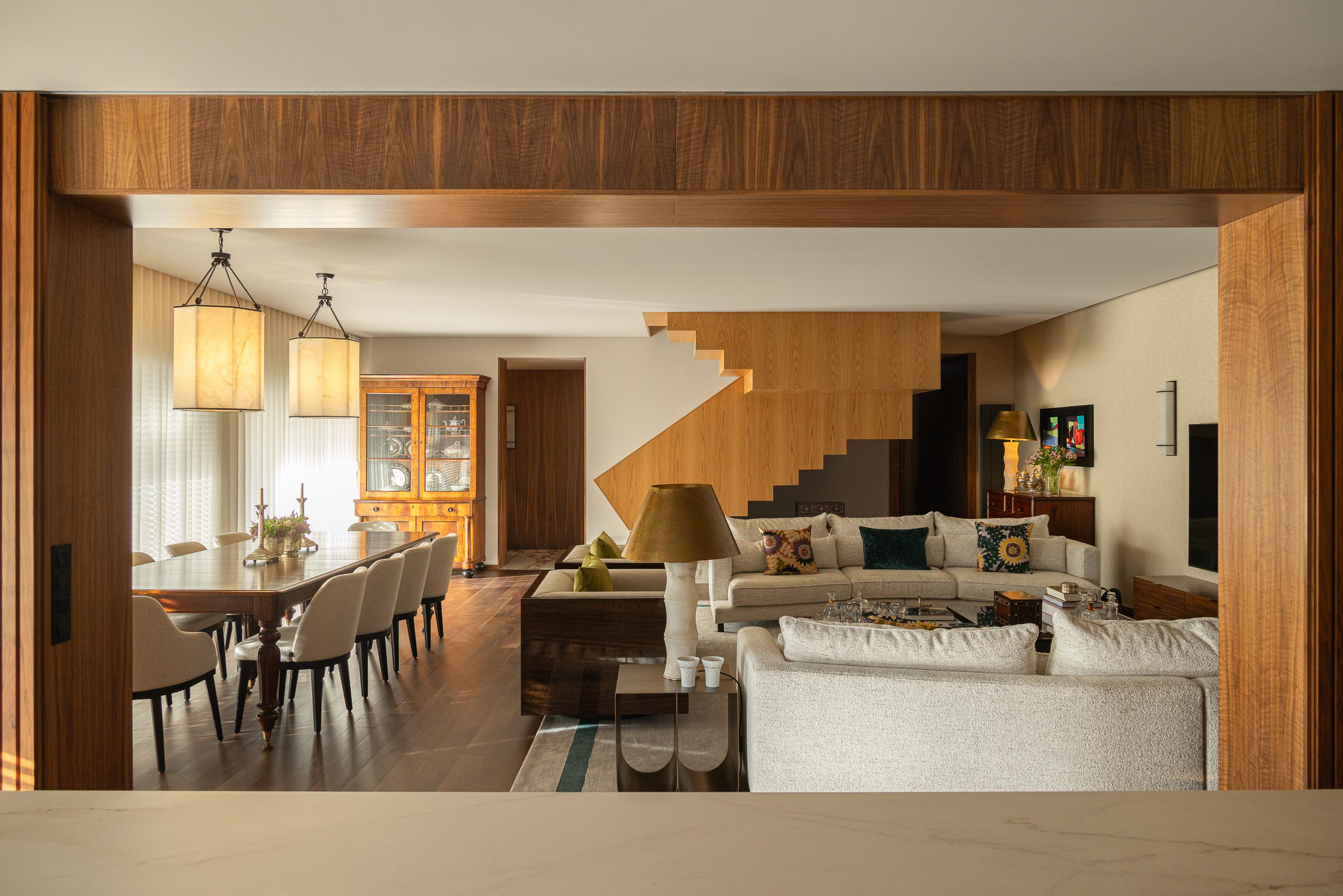 Sala de estar: Vista da sala de estar a partir da cozinha, com escadas em madeira e mármore e estantes em madeira escura. — Casa do Engenho arquitetura silverline em Vila Nova de Gaia