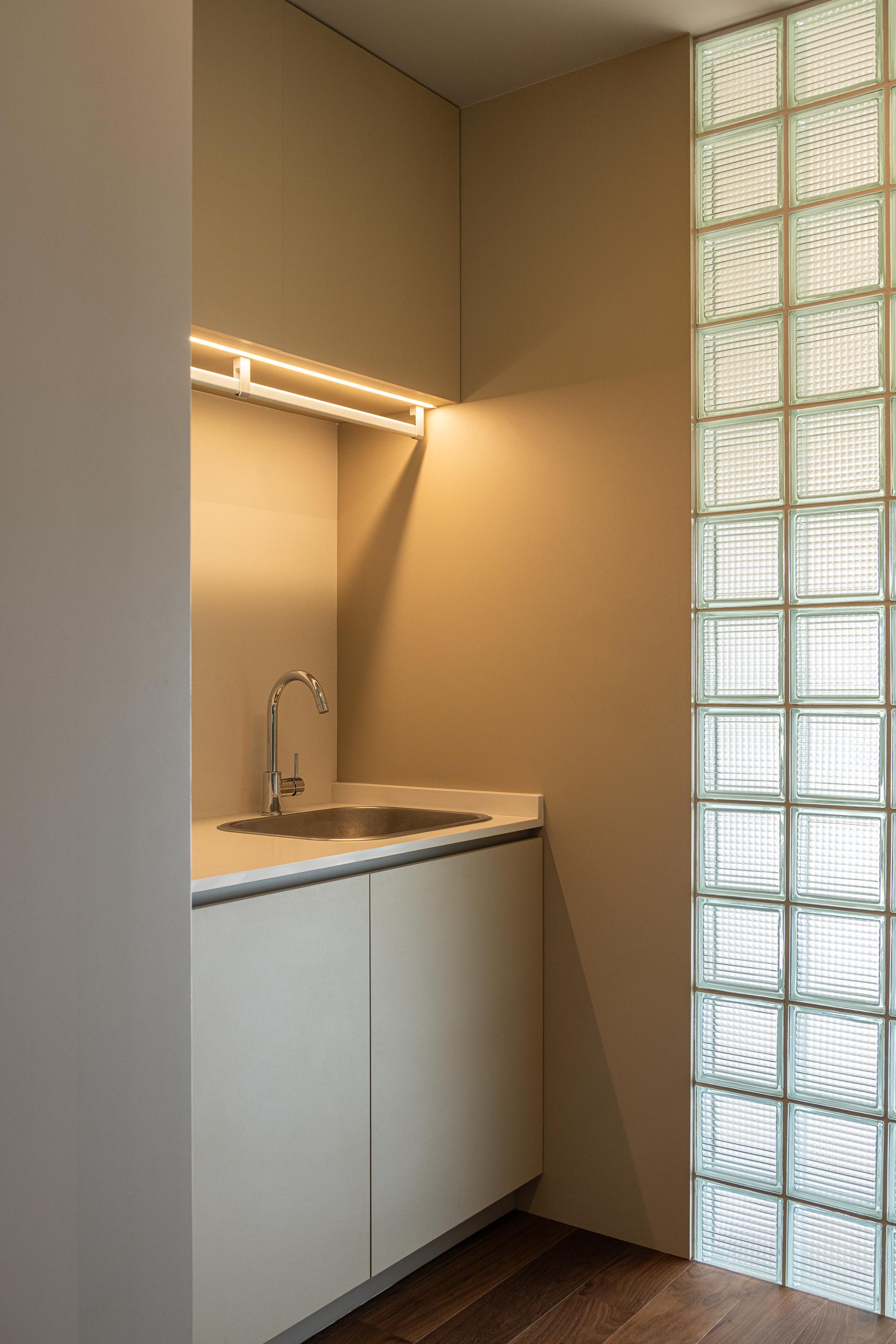 Lavandaria: Lavatório com armários brancos e parede de blocos de vidro. — Casa do Engenho arquitetura silverline em Vila Nova de Gaia