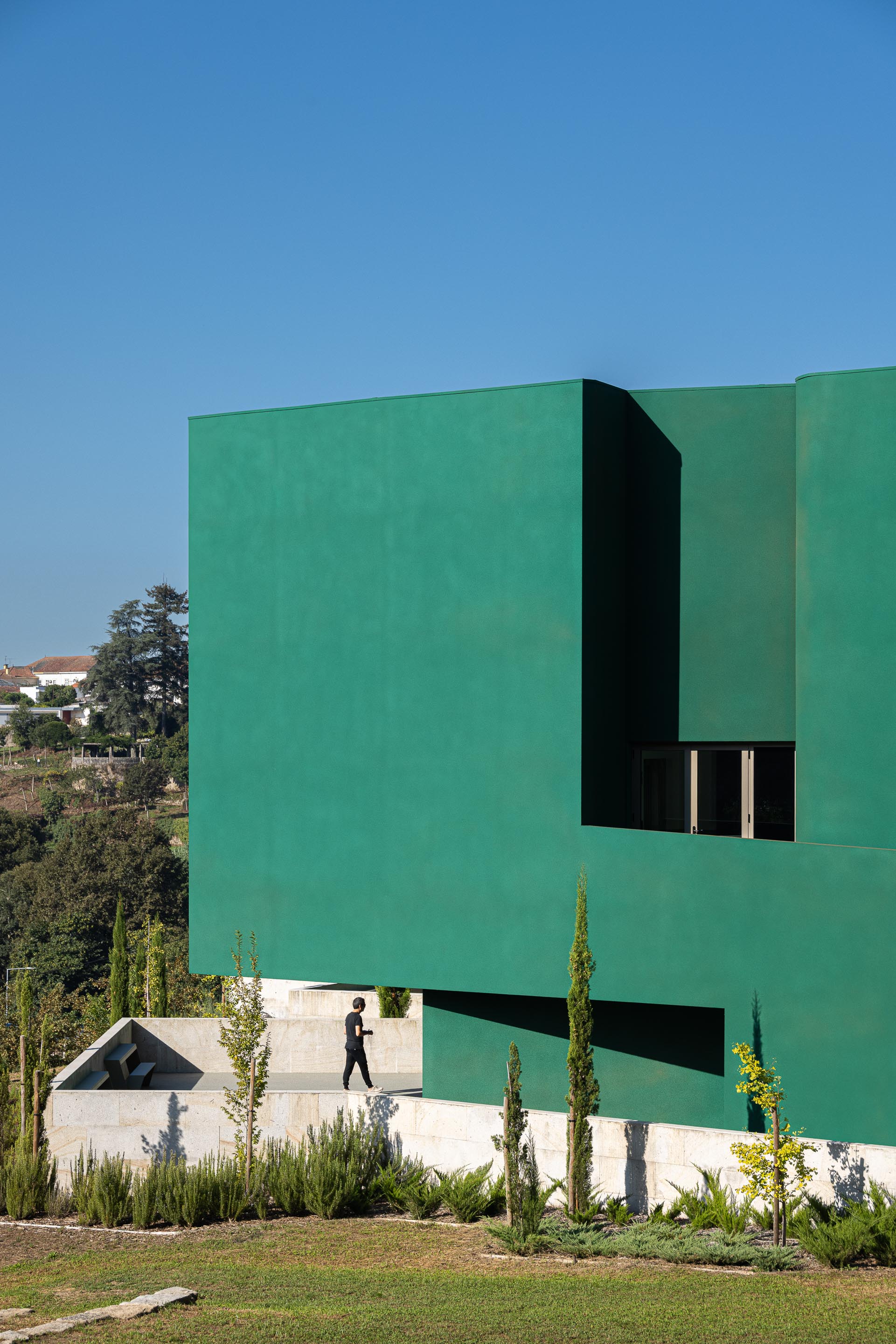 Fachada: Vista lateral do edifício verde com detalhes arquitetónicos e paisagismo. — Ponto C - Cultura e Criatividade arquitetura Galeria Gabinete em Penafiel