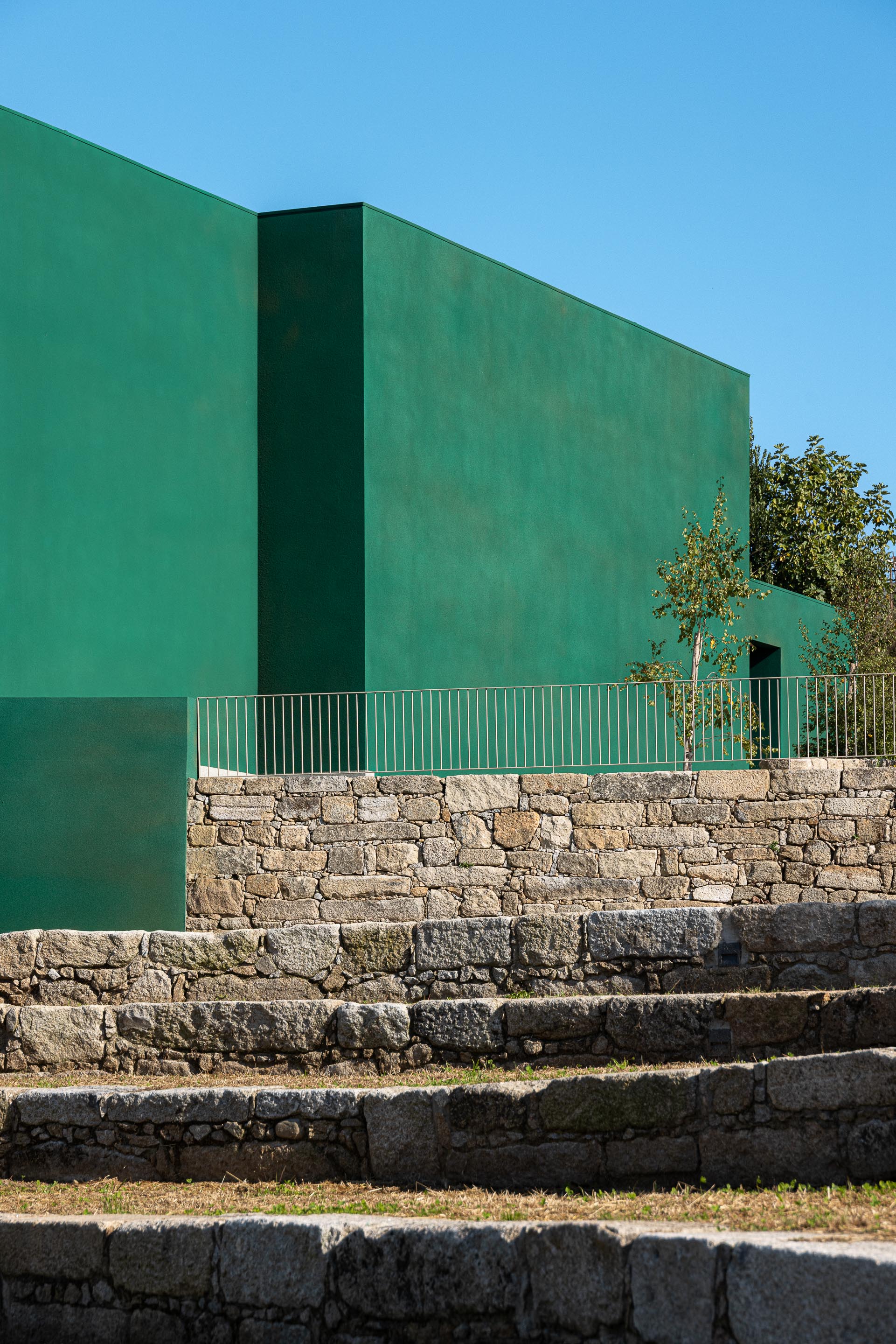 Fachada: Detalhe da fachada verde com muro de pedra e escadas de acesso. — Ponto C - Cultura e Criatividade arquitetura Galeria Gabinete em Penafiel