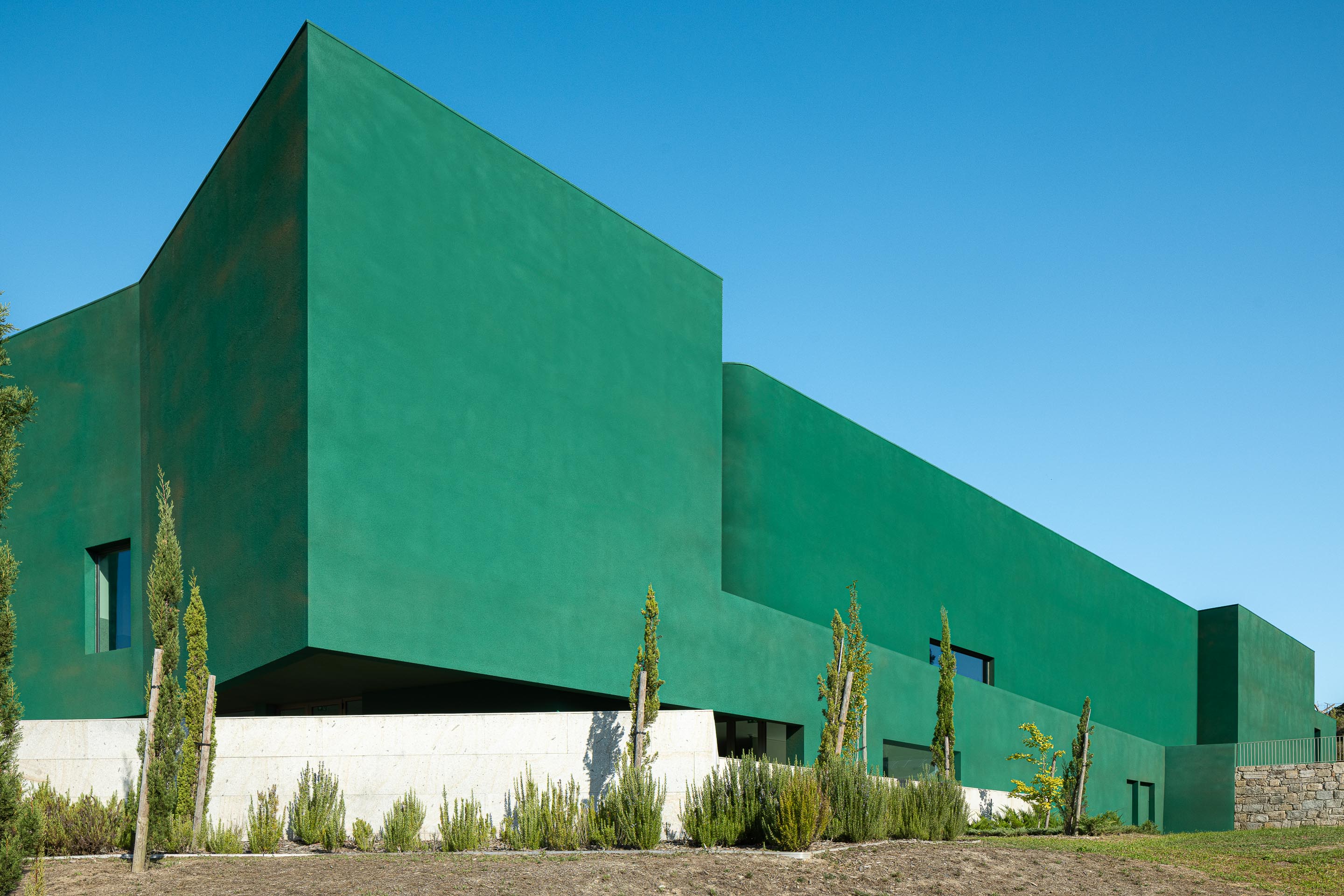 Fachada: Perspectiva do edifício verde, com linhas geométricas e paisagismo. — Ponto C - Cultura e Criatividade arquitetura Galeria Gabinete em Penafiel