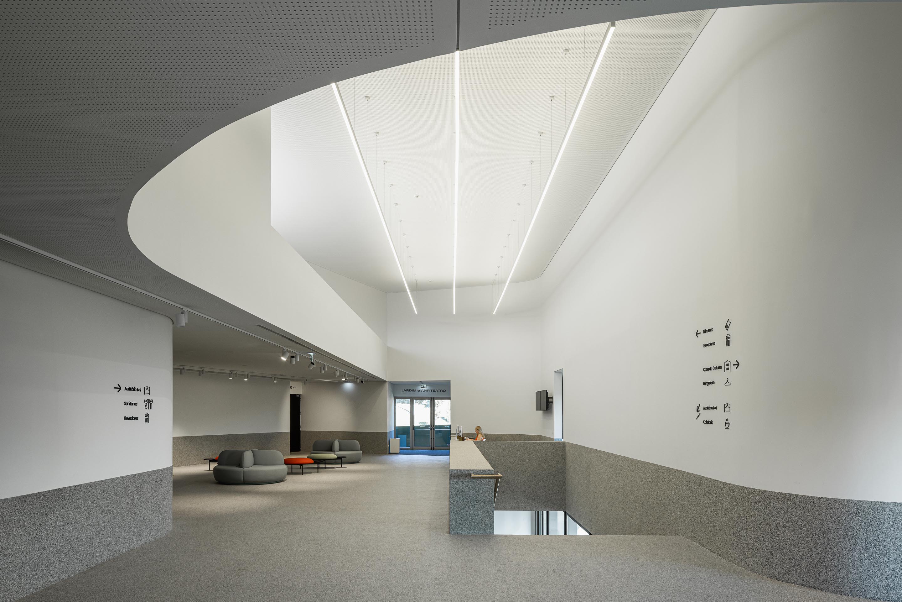 Hall de entrada: Espaço amplo com teto perfurado, iluminação linear e zona de receção. — Ponto C - Cultura e Criatividade arquitetura Galeria Gabinete em Penafiel