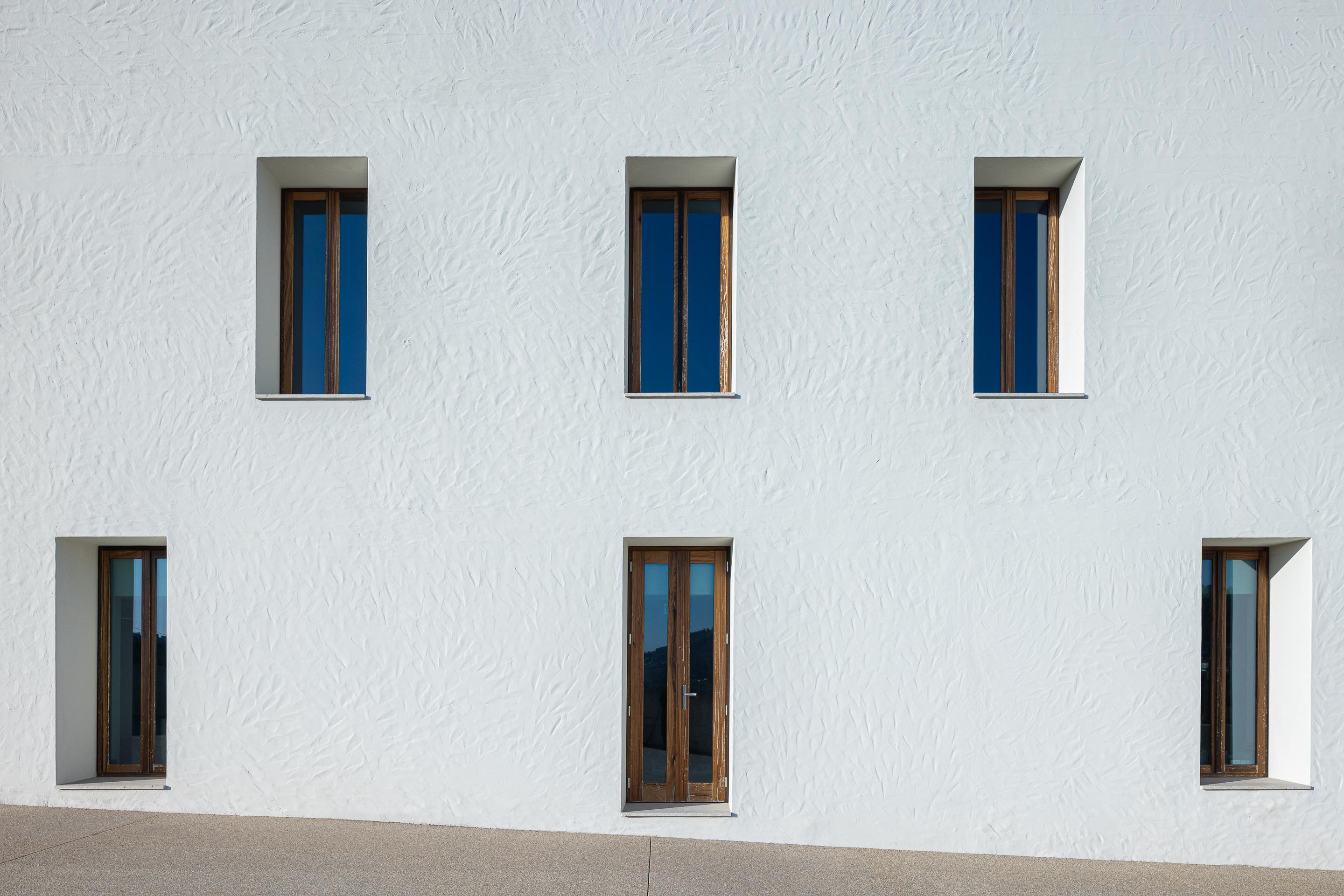 Fachada: Edifício branco com janelas e porta em madeira, com textura rústica. — Ponto C - Cultura e Criatividade arquitetura Galeria Gabinete em Penafiel