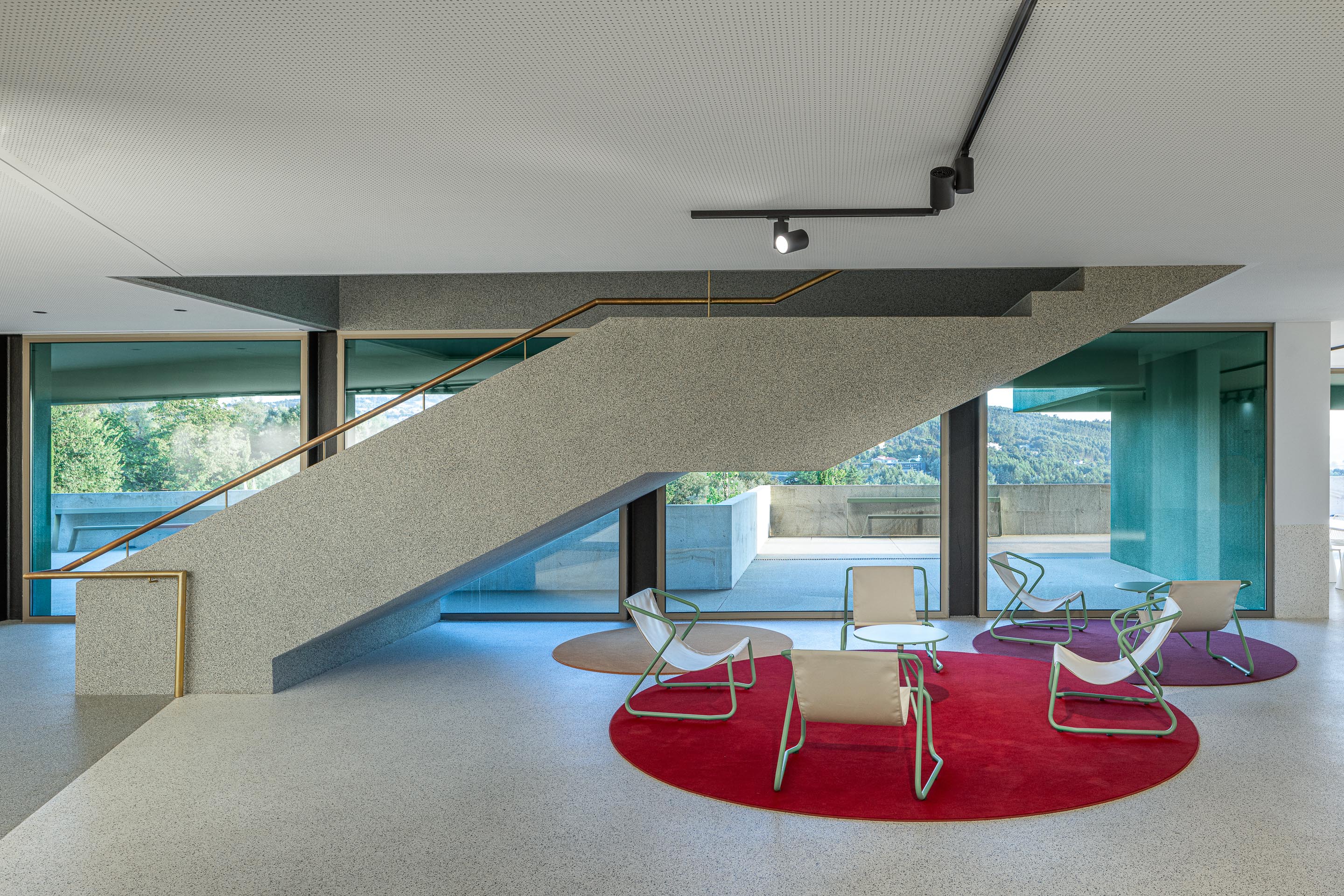 Hall de entrada: Escadas com corrimão dourado e zona de estar com alcatifas circulares coloridas. — Ponto C - Cultura e Criatividade arquitetura Galeria Gabinete em Penafiel