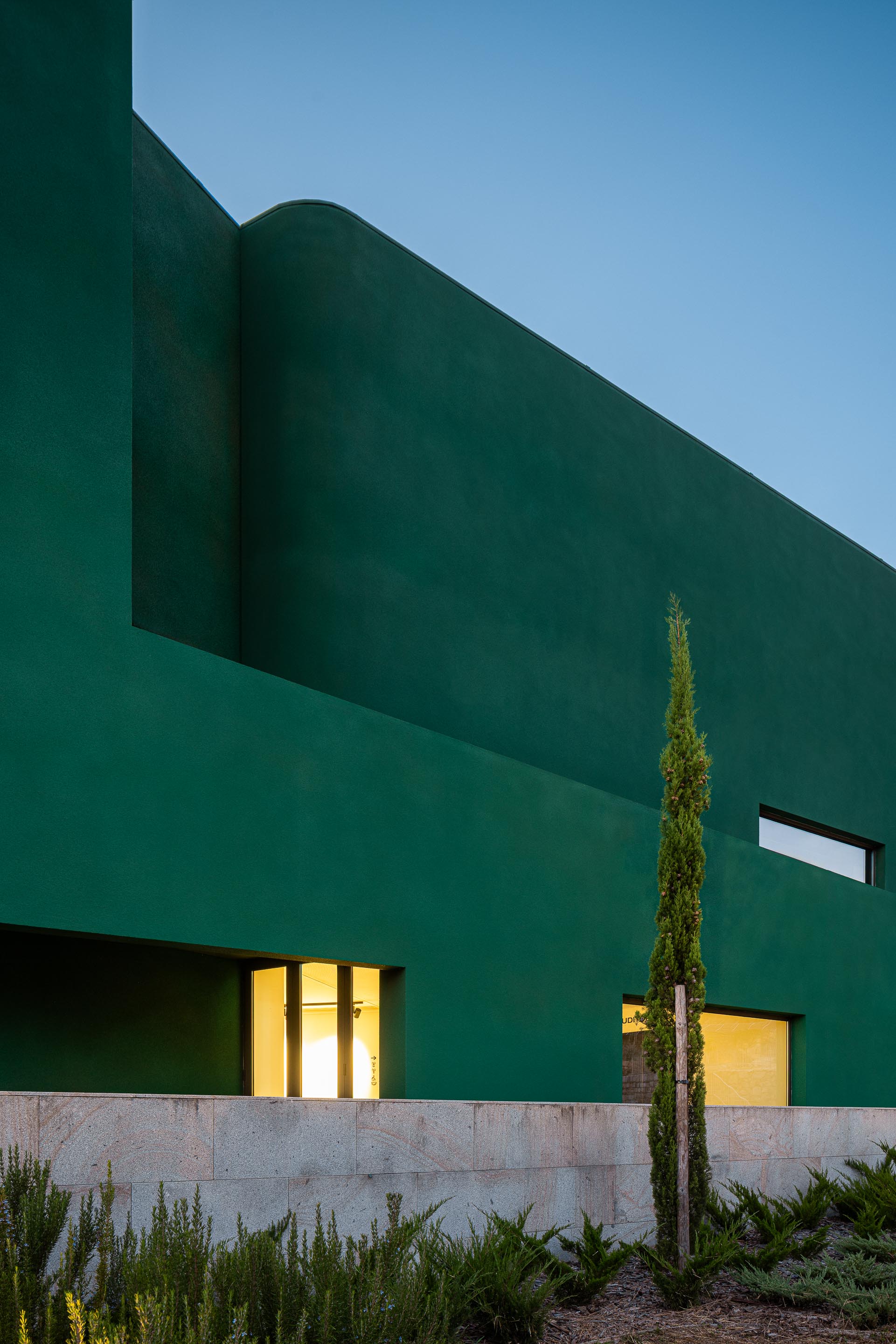 Fachada: Detalhe da fachada verde com janelas e vegetação rasteira. — Ponto C - Cultura e Criatividade arquitetura Galeria Gabinete em Penafiel