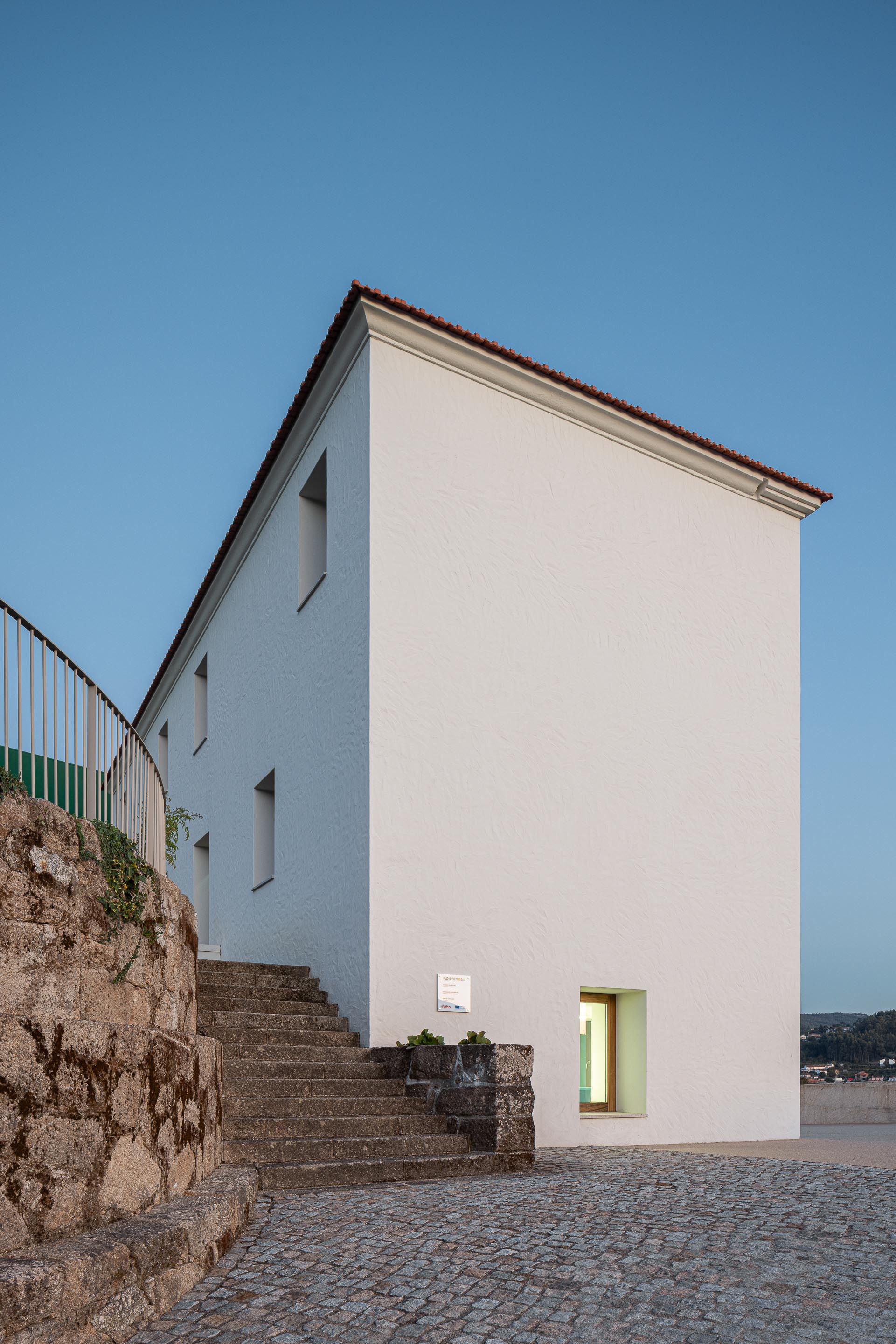 Exterior: Edifício branco com escadas de acesso e muro de pedra. — Ponto C - Cultura e Criatividade arquitetura Galeria Gabinete em Penafiel
