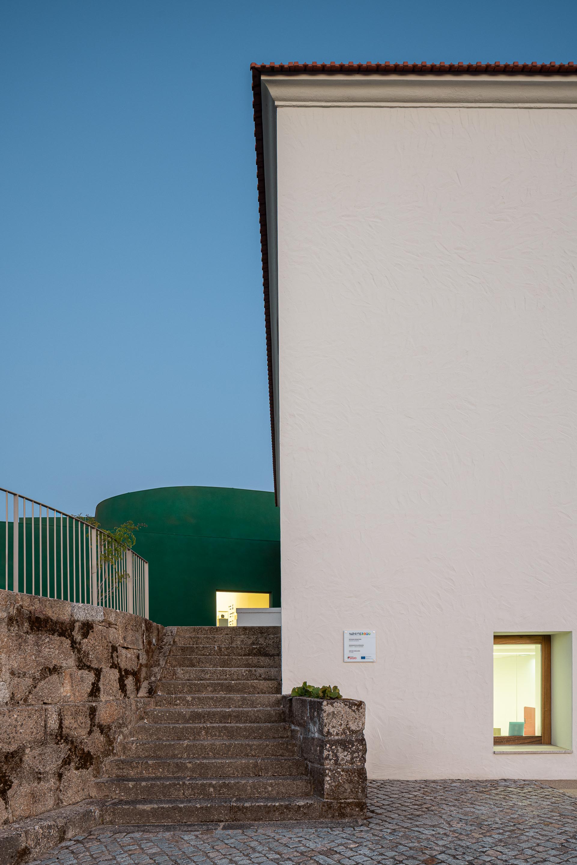 Exterior: Edifício branco com escadas de acesso e edifício verde ao fundo. — Ponto C - Cultura e Criatividade arquitetura Galeria Gabinete em Penafiel