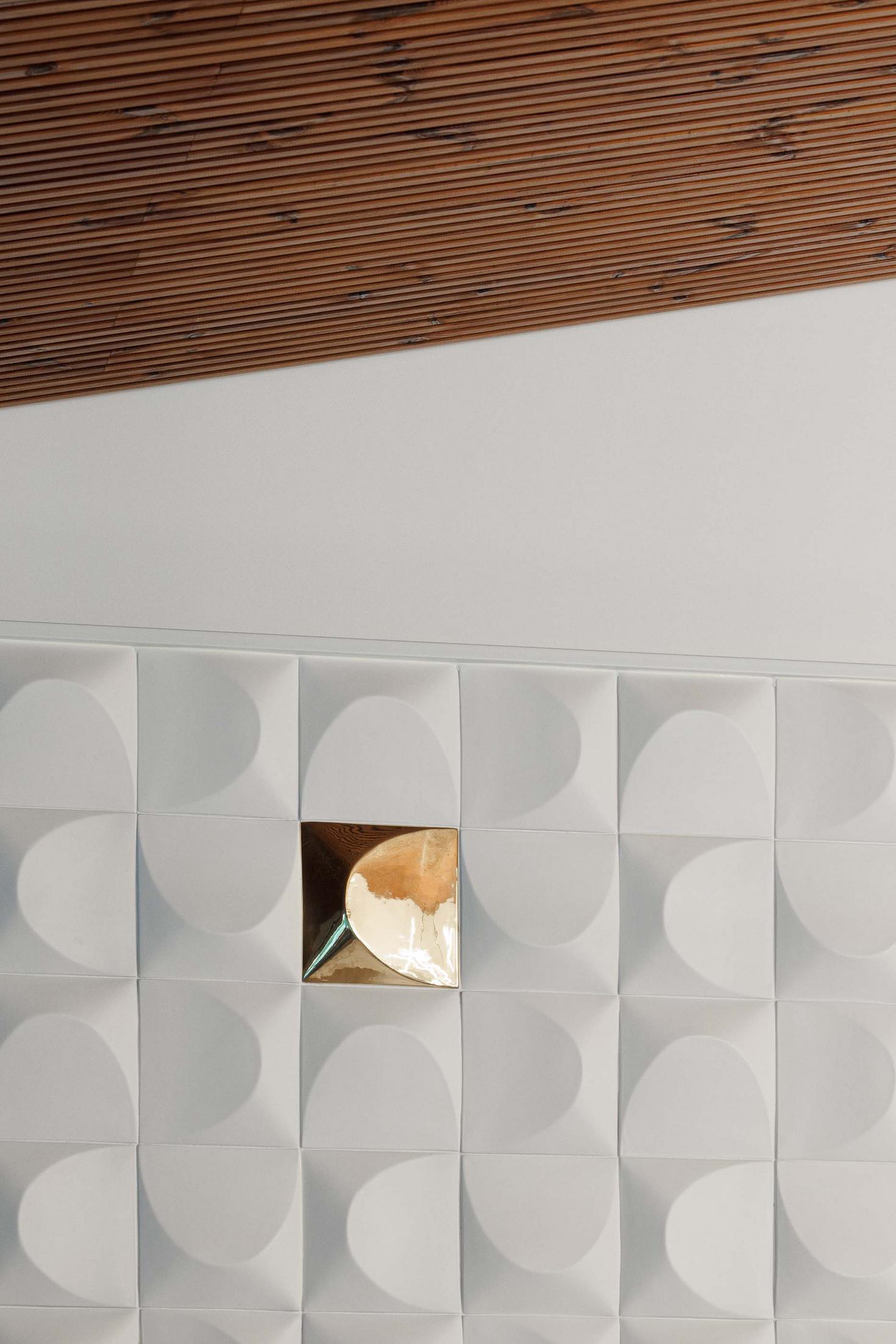 Cozinha: Detalhe da parede com revestimento branco texturado e nicho dourado. — CC House – Quinta dos Carvalhos arquitetura Inception Architects Studio em Leiria