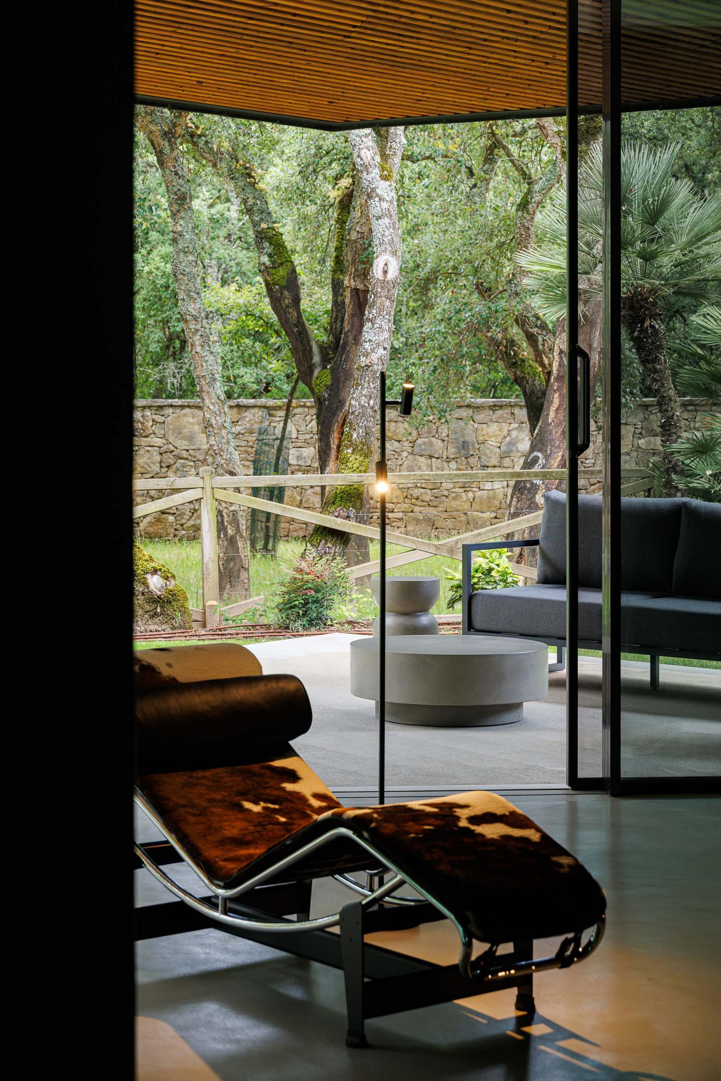 Alpendre: Espreguiçadeira em couro, candeeiro de pé e vista para o jardim. — CC House – Quinta dos Carvalhos arquitetura Inception Architects Studio em Leiria