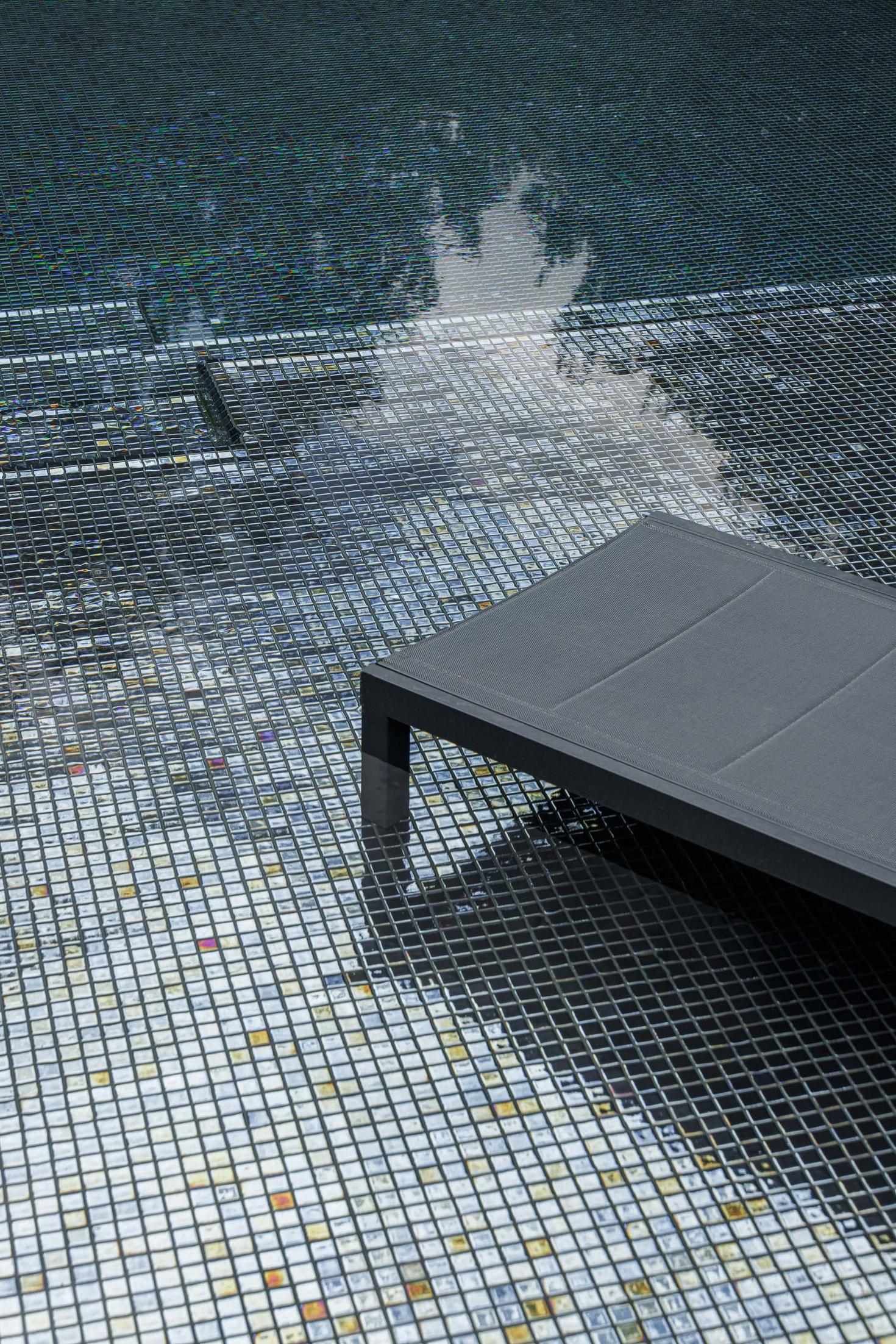 Piscina: Detalhe da piscina com mosaicos e espreguiçadeira preta. — CC House – Quinta dos Carvalhos arquitetura Inception Architects Studio em Leiria