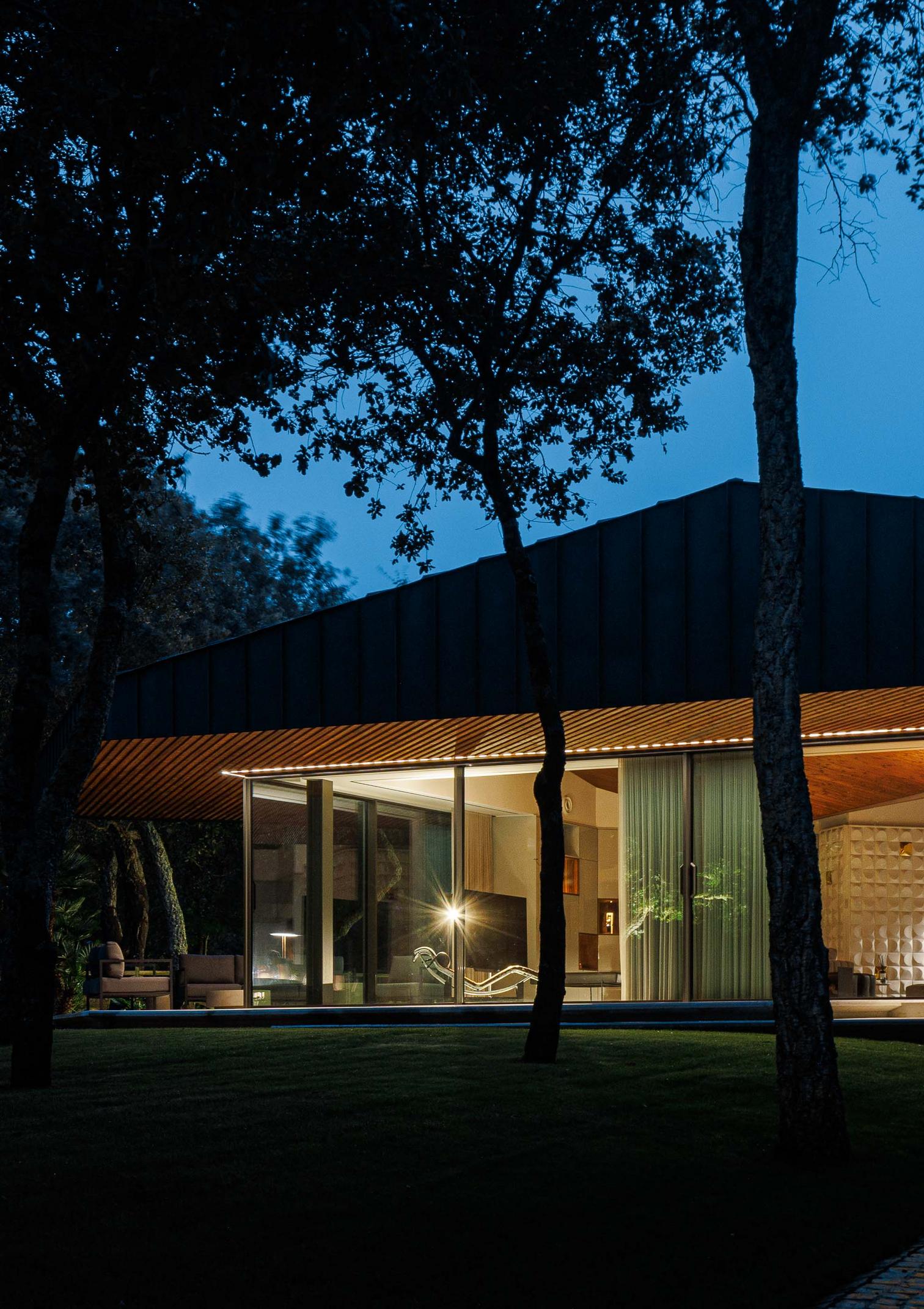 Exterior: Vista noturna da casa com iluminação interior e exterior. — CC House – Quinta dos Carvalhos arquitetura Inception Architects Studio em Leiria