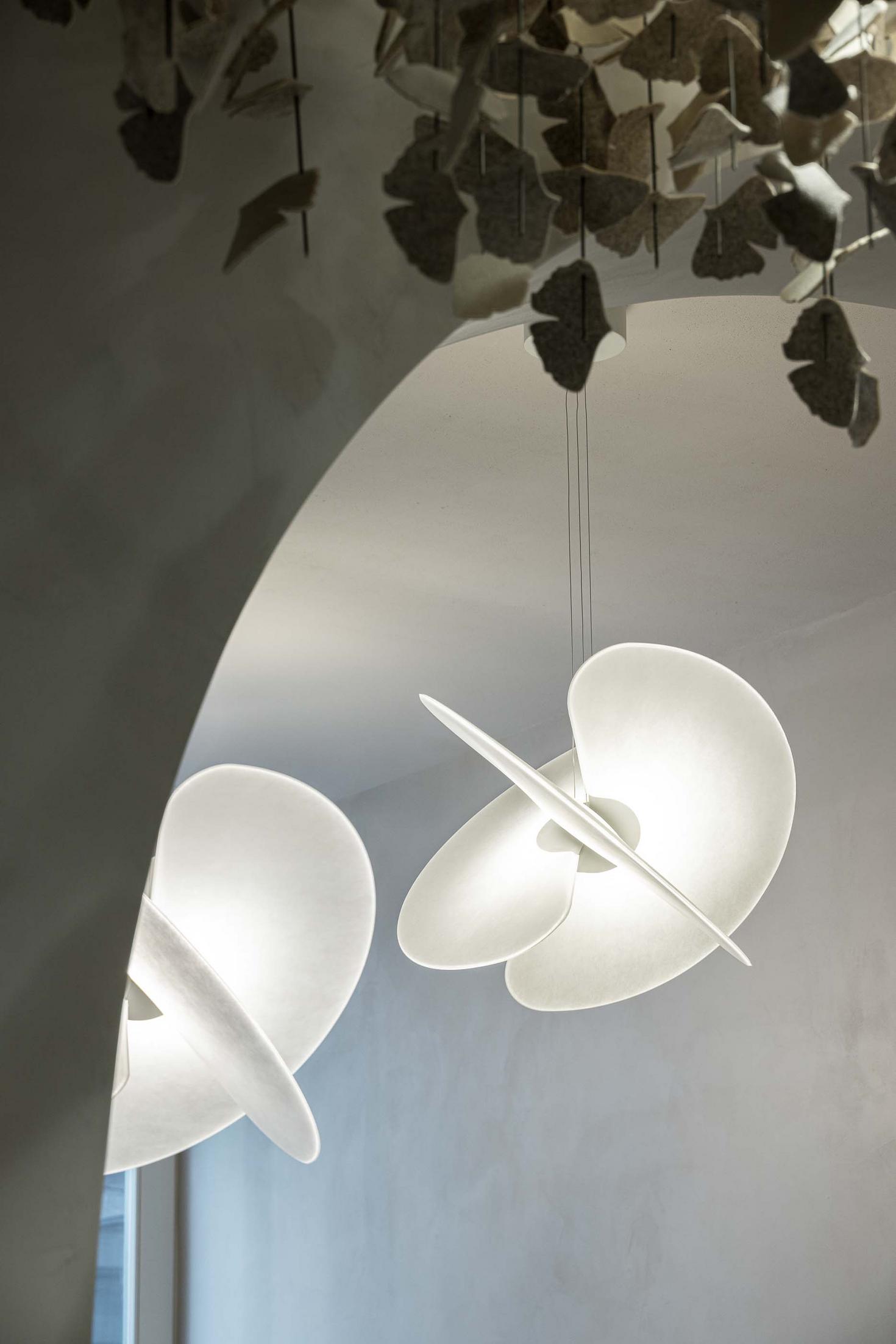 Bar: Balcão em aço inoxidável com prateleiras iluminadas, garrafas e máquina de café sob um teto com folhagens. — The Capsule Neo-Bistro arquitetura Atelier Réalité em Lisboa