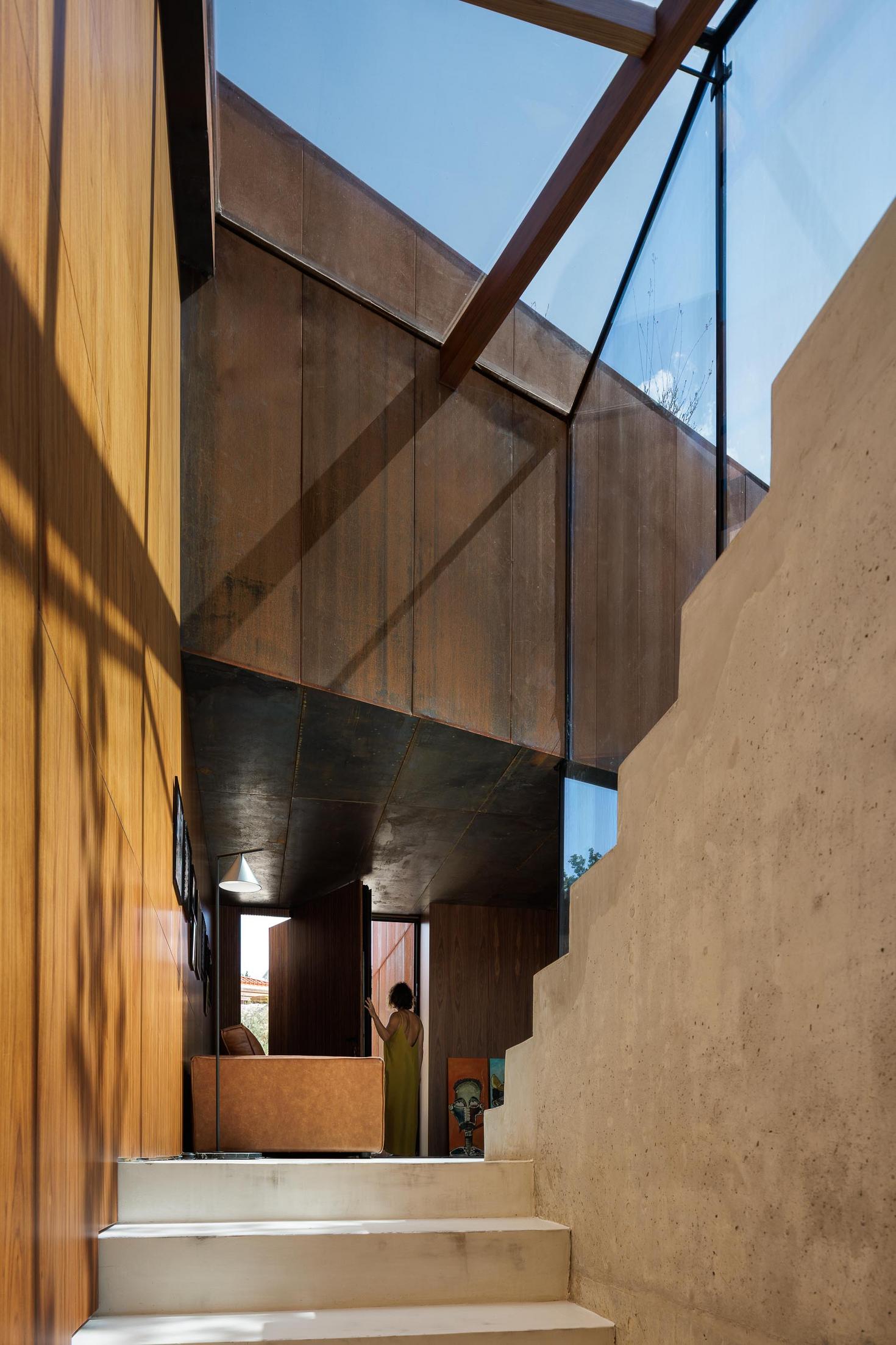 Escadas: Escadas interiores com degraus brancos, paredes em madeira e aço corten, com claraboia no topo. — Casa Corten arquitetura HPA Arquitetura e Investimentos em Celorico de Basto