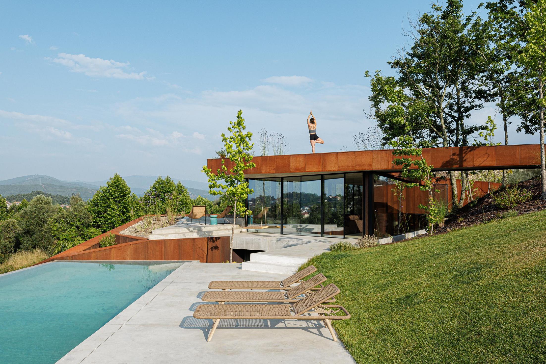 Exterior: Piscina com espreguiçadeiras, relvado e vista panorâmica sobre a paisagem. — Casa Corten arquitetura HPA Arquitetura e Investimentos em Celorico de Basto