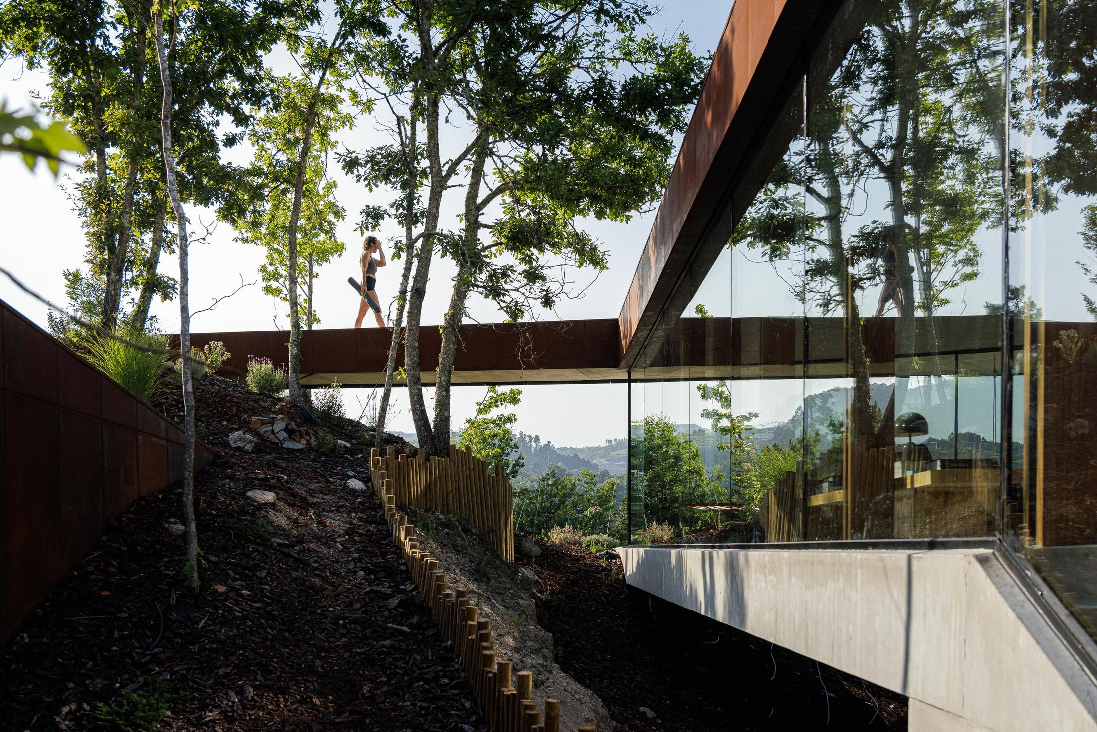 Exterior: Passadiço em aço corten que liga diferentes áreas da casa, com vista para a paisagem. — Casa Corten arquitetura HPA Arquitetura e Investimentos em Celorico de Basto