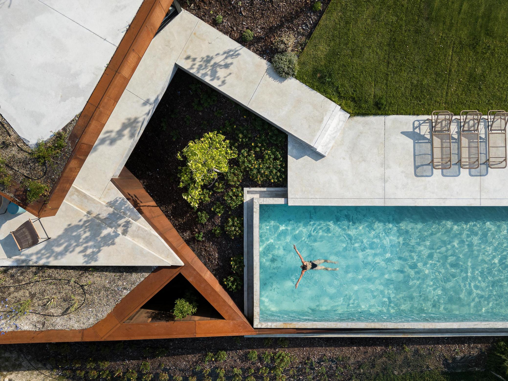 Piscina: Detalhe de mulher a tocar na água da piscina, com borda infinita e reflexos. — Casa Corten arquitetura HPA Arquitetura e Investimentos em Celorico de Basto