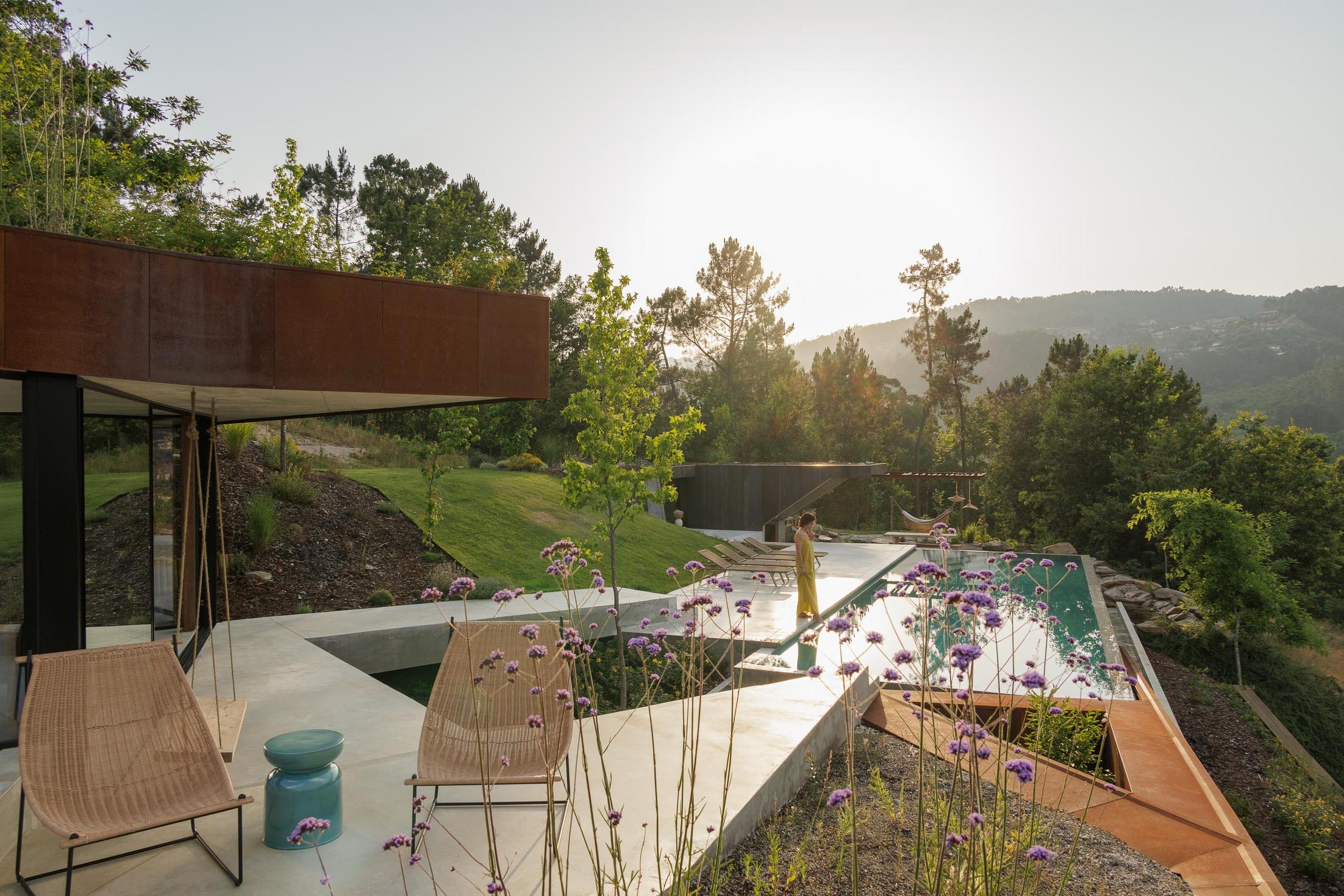 Escadas: Escadas exteriores com degraus brancos, paredes em madeira e claraboia iluminada ao anoitecer. — Casa Corten arquitetura HPA Arquitetura e Investimentos em Celorico de Basto